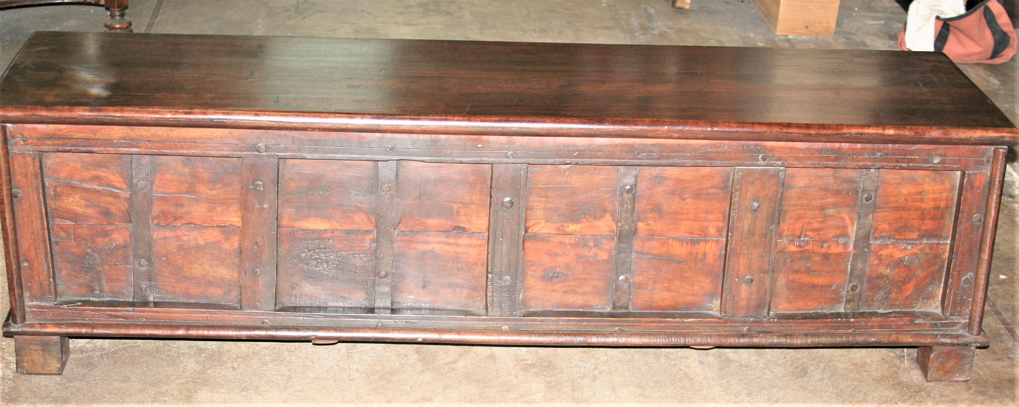 This chest was originally crafted as linen chest in the 19th century but later modified as a storage cum bench for placing behind the foot board of king size beds. This makes it a superb conversation piece for any grand bed room. The lid opens to a