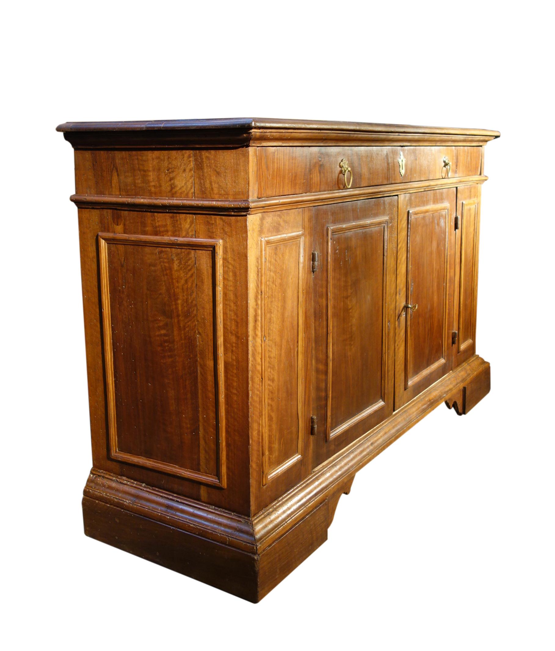 19th Century solid walnut Italian credenza with veneers, with pair of doors and single drawer. Simple, sturdy Tuscan style with brass hardware. Interior is clean with single fixed shelf. Lock and key on the right side door with interior shelf latch