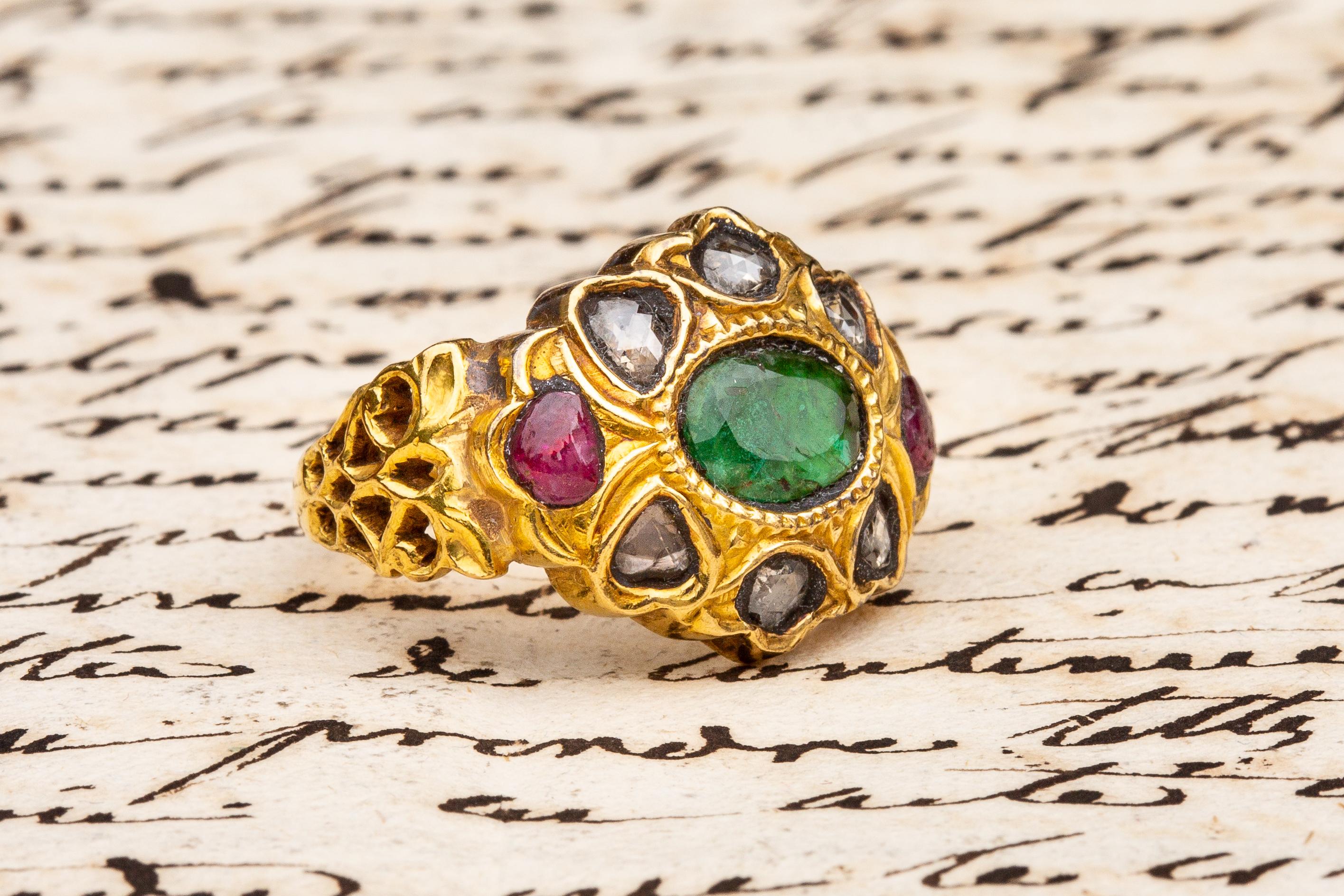 A scarce 19th century Indian emerald, ruby and diamond gold cluster ring, from Deccan or South India. The gem-set cluster takes a floral form, the central emerald is surrounded on all sides by cabochon rubies and flat-cut diamonds in foiled,