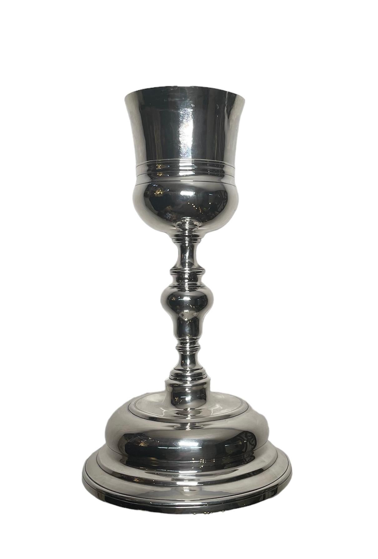 Dies ist ein spanischer Silberkelch aus dem 19. Jahrhundert. Sie zeigt einen glockenförmigen Becher, der von einem balusterartigen Stiel getragen wird und auf einem runden, dreistufigen Sockel steht. Am Rand des Sockels befindet sich die Punze