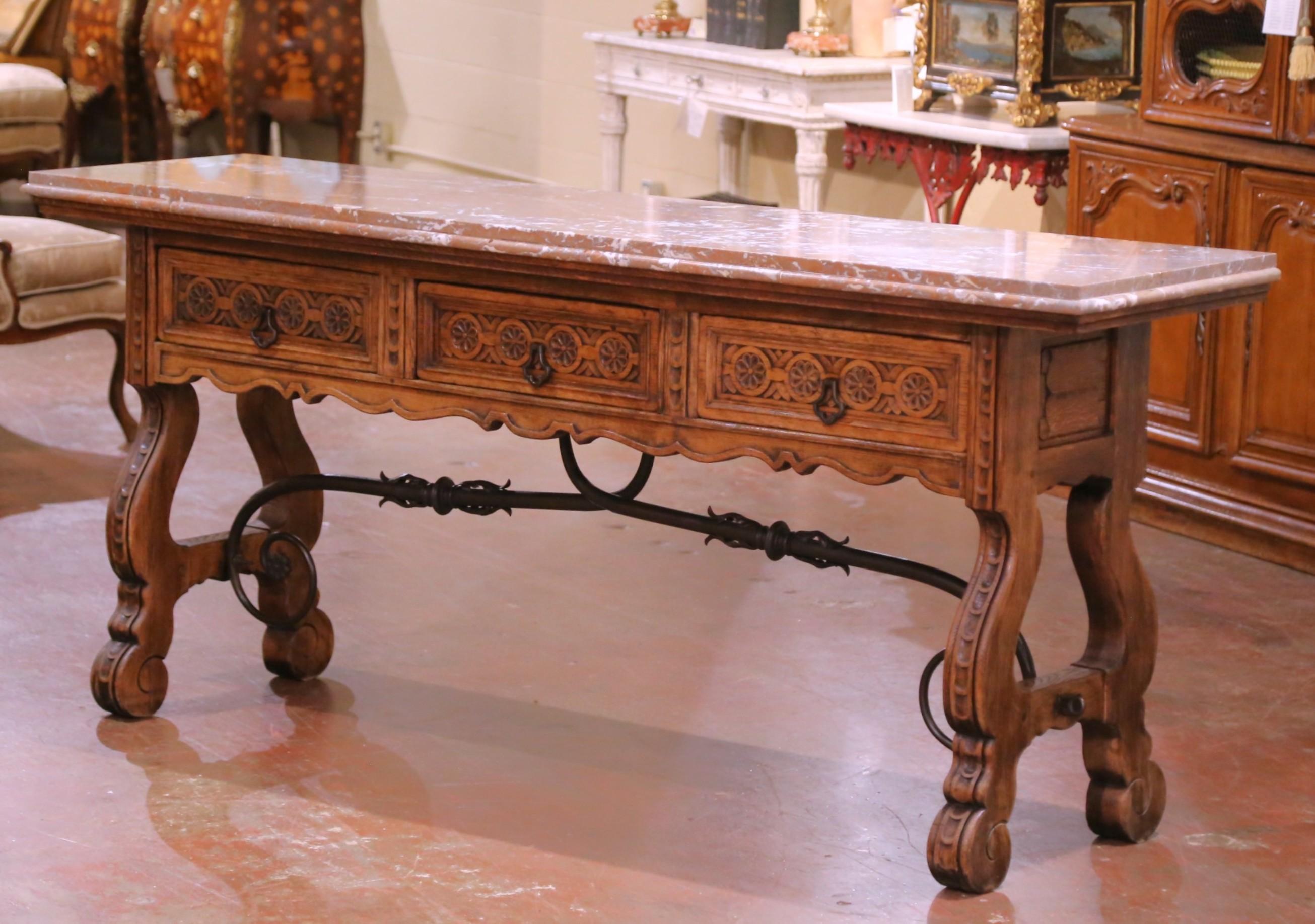 Bring rustic refinement and classical detail to an interior with this striking antique console table. Crafted in Spain circa 1860, the piece features a richly carved oak base topped with a substantial slab of Breccia Pernice marble, prized for its