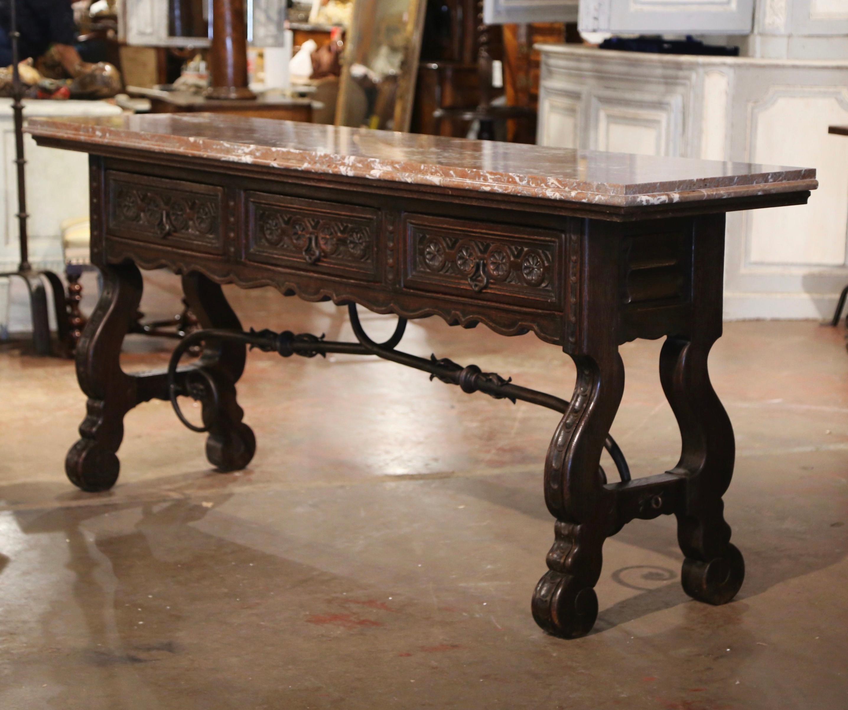 Add an elegant focal point to your entry, hallway or living room with this beautiful antique carved console table. Carved in Spain circa 1850, the trestle console stands on intricate carved ox yoke supports, connected with a thick, forged iron