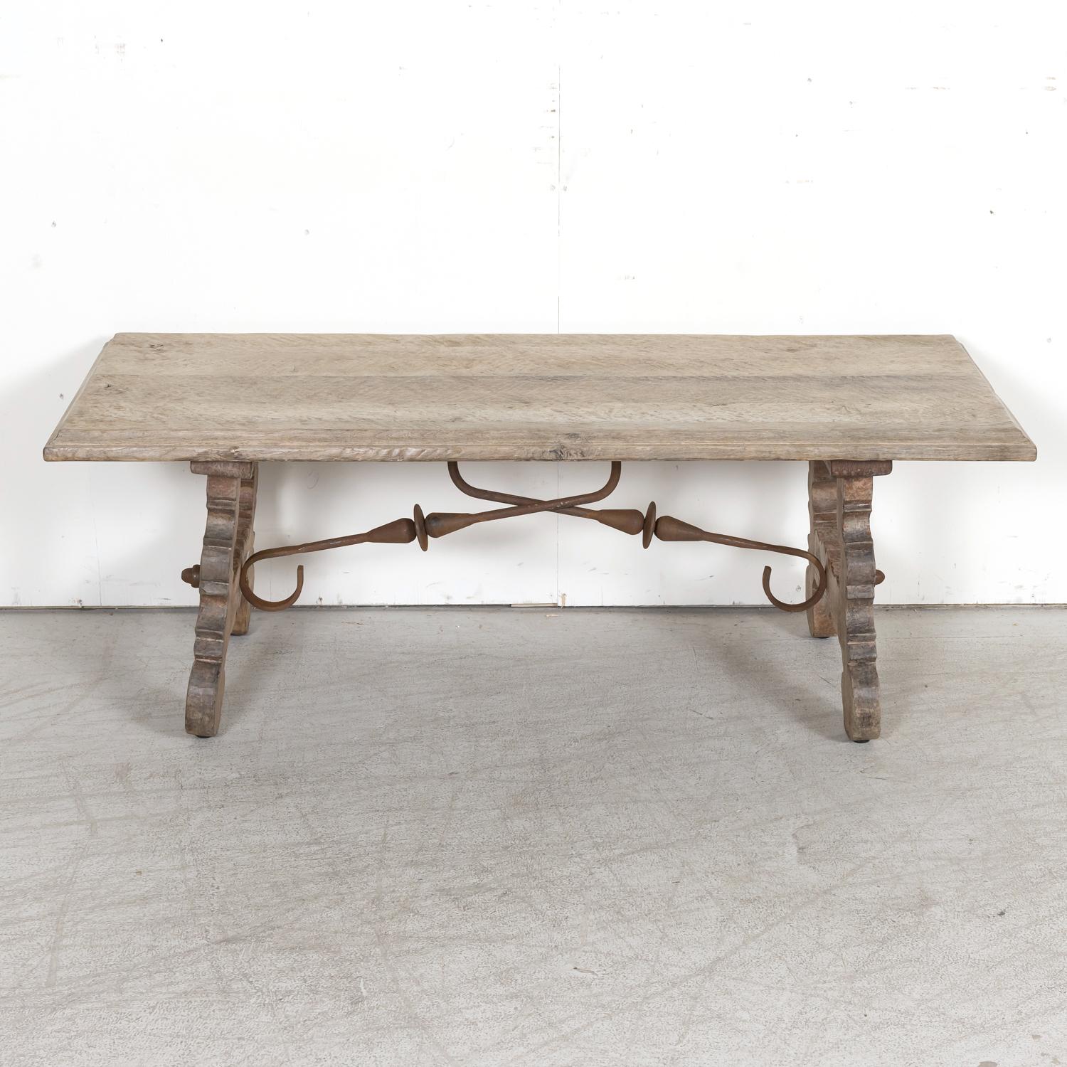 A 19th century Spanish Baroque style coffee table, circa 1880s, from the Catalan region handcrafted of solid oak with a bleached or washed finish and handsome grain pattern. Having a beveled edge plank top resting on carved lyre-shaped legs joined