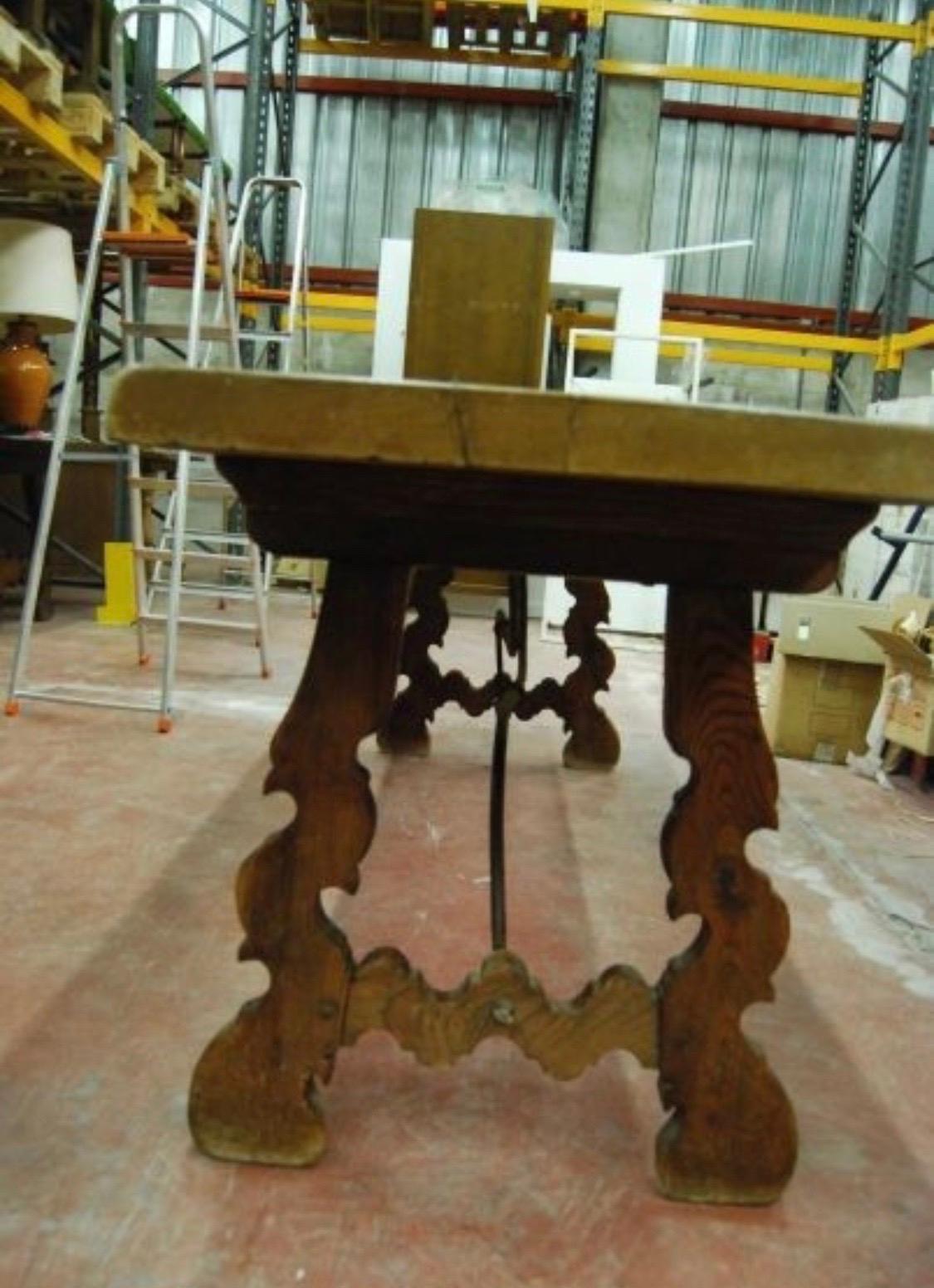 Ein monumentaler spanischer Bocktisch aus dem 19. Jahrhundert mit einer rechteckigen, gerahmten Platte aus massivem Nussbaumholz, die auf handgeschnitzten, klassischen Lyra-Beinen ruht, die durch vier schöne Eisentragen verbunden sind.

Dieser