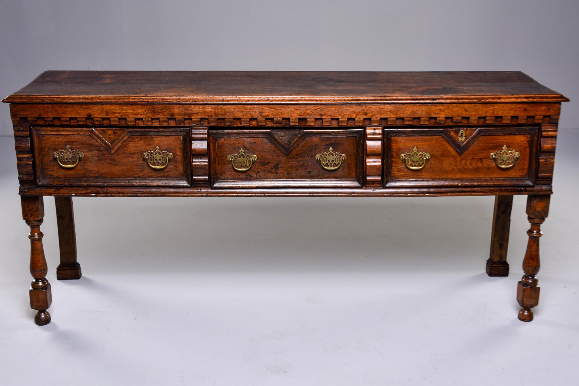 Circa 1820s Spanish baroque table in walnut features carved details, turned front legs and three functional drawers with fancy brass hardware. Unknown maker.