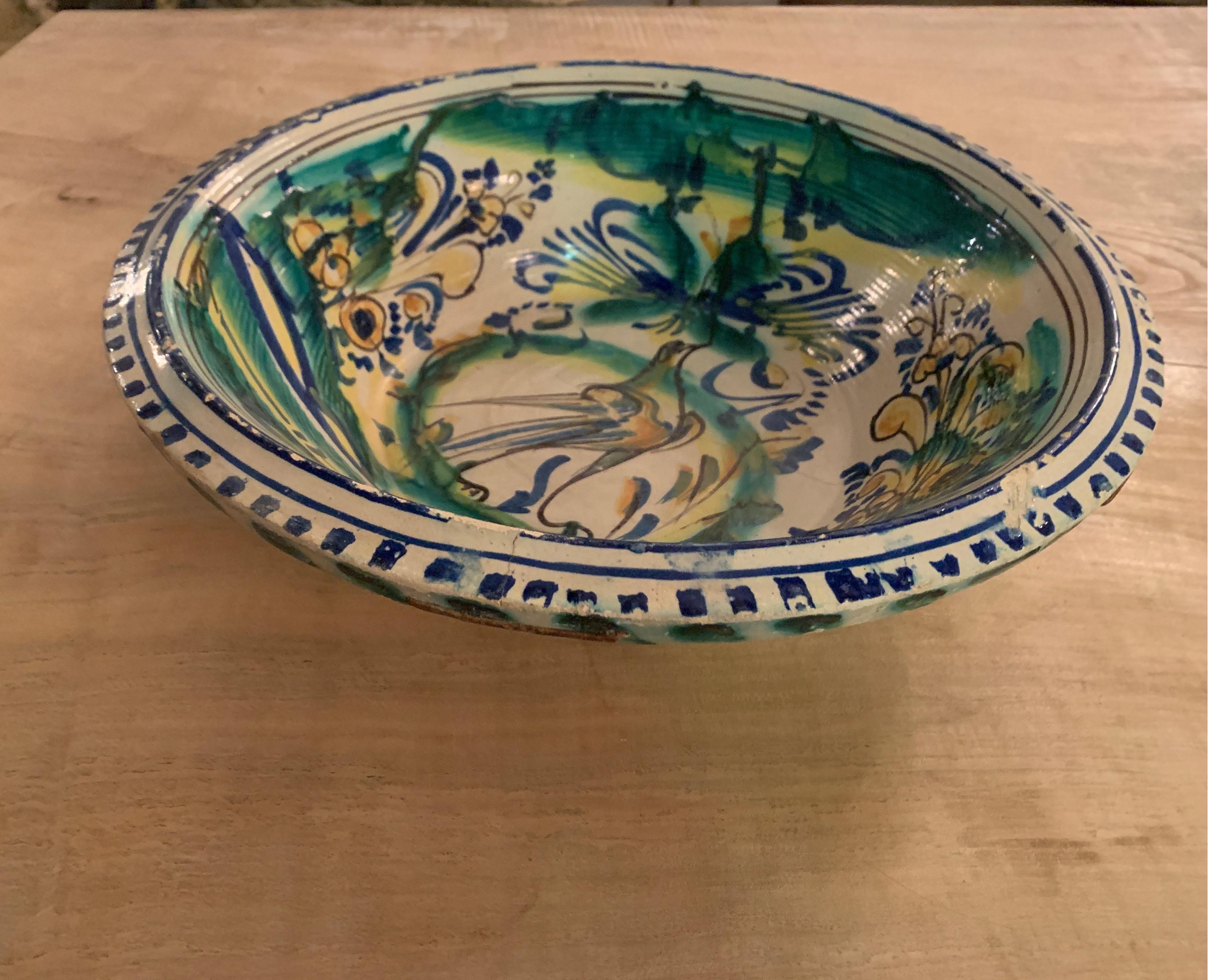This is a wonderful design of bird in bright colors of yellow, greens and blues on decorative bowl from the Andalusia region of Spain. It has great character with the staple repairs as well.