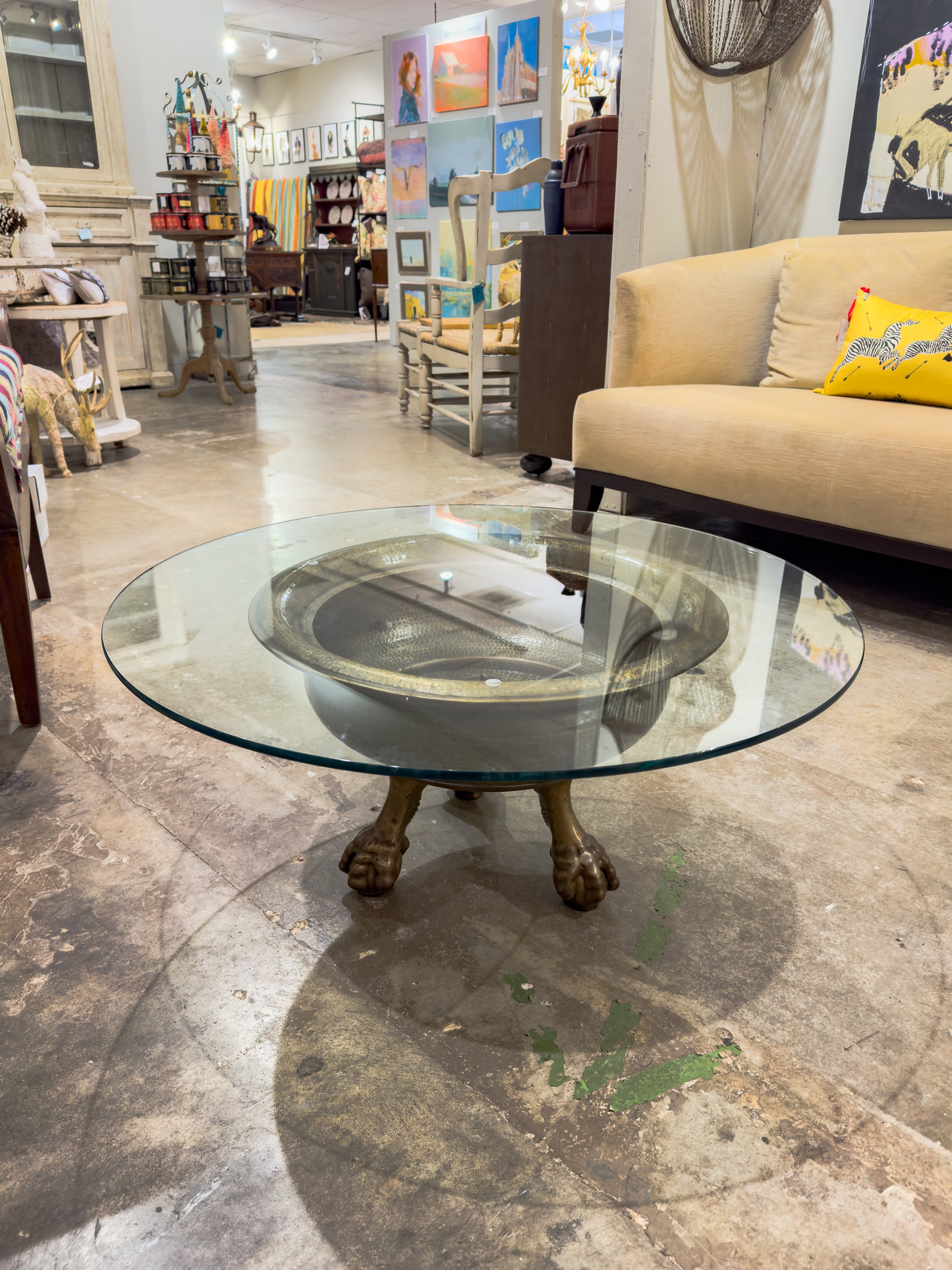 The 19th Century Spanish Brass Ball and Clawfoot Brazier, transformed into a functional table with a glass top, stands as a remarkable testament to both history and adaptability. Originally recognized as 