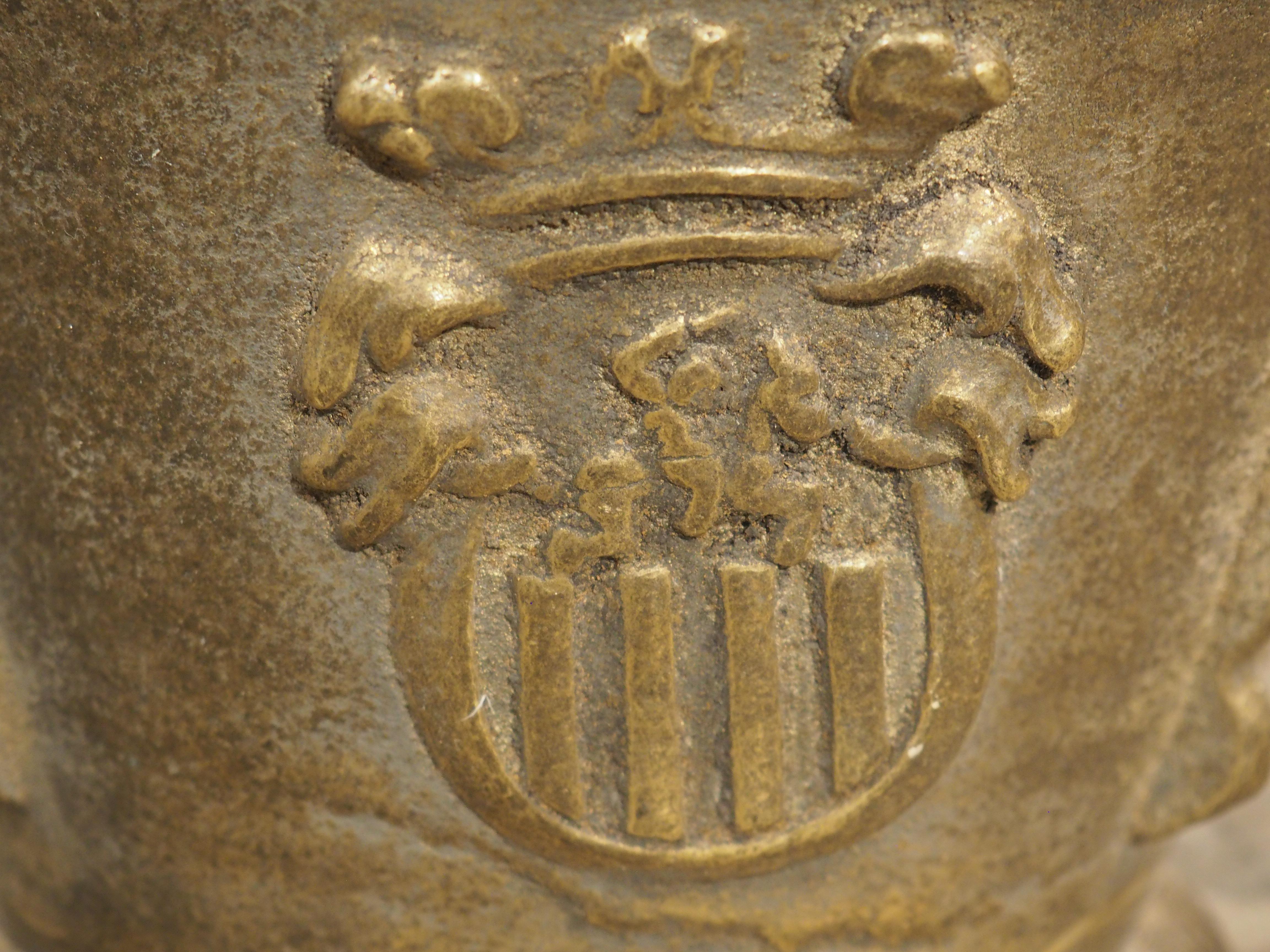 Questo unico mortaio e pestello in bronzo sarebbe stato utilizzato in una spezieria spagnola durante il 1800. Un paio di cani rivolti verso il basso fungono da maniglie che si estendono ben oltre il corpo principale. Sotto le due teste canine ci