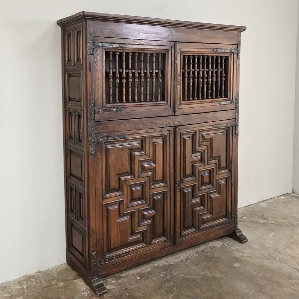 19th century Spanish cabinet was designed as a kitchen cabinet, and created from framed heavily chamfered panels affixed to the casework with massive hand-forged strap hinges. Nine such panels appear on the sides, with spindle rails affixed in what