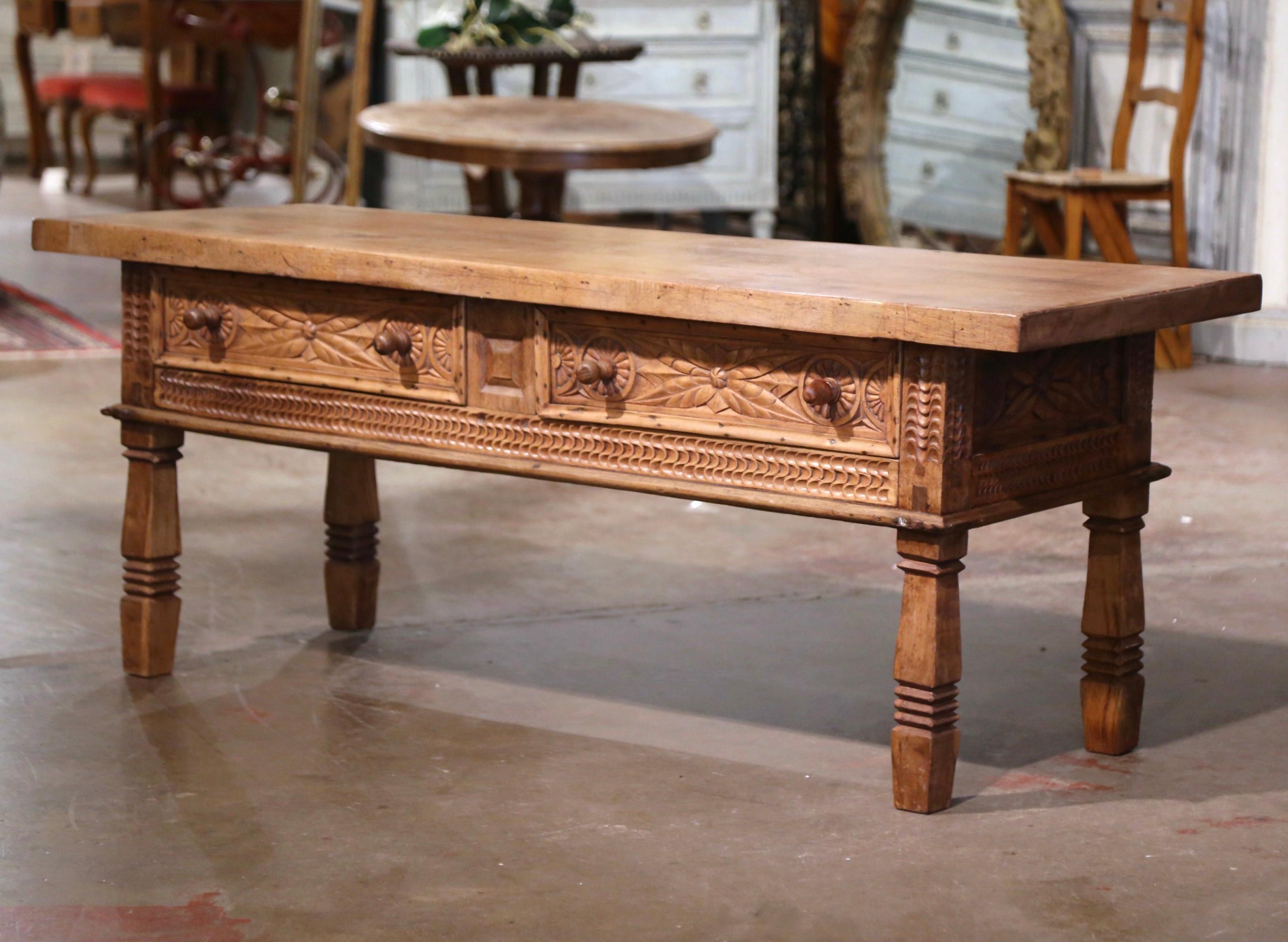 Decorate a den or living room with this elegant antique coffee table. Created in Spain, circa 1850 and richly carved all around, the long table stands on four carved turned legs. The Baroque table features two drawers across the front decorated with