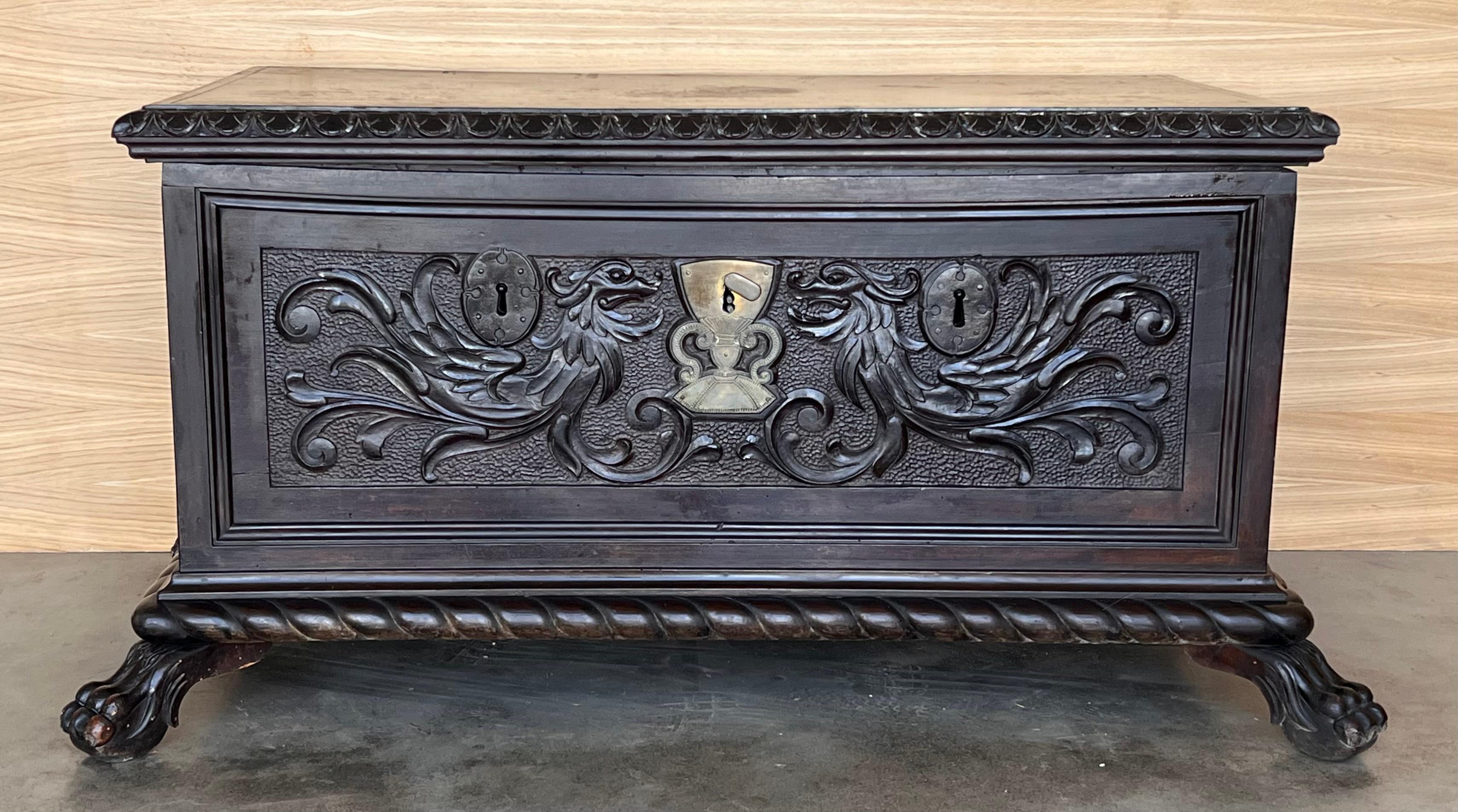 Placez cet élégant coffret ancien au pied d'un lit king size. Fabriqué en Espagne, vers 1800, ce coffre rectangulaire repose sur des pieds en forme d'équerre. Fortement sculpté sur les trois côtés avec un décor d'arcs et de feuillages, le meuble