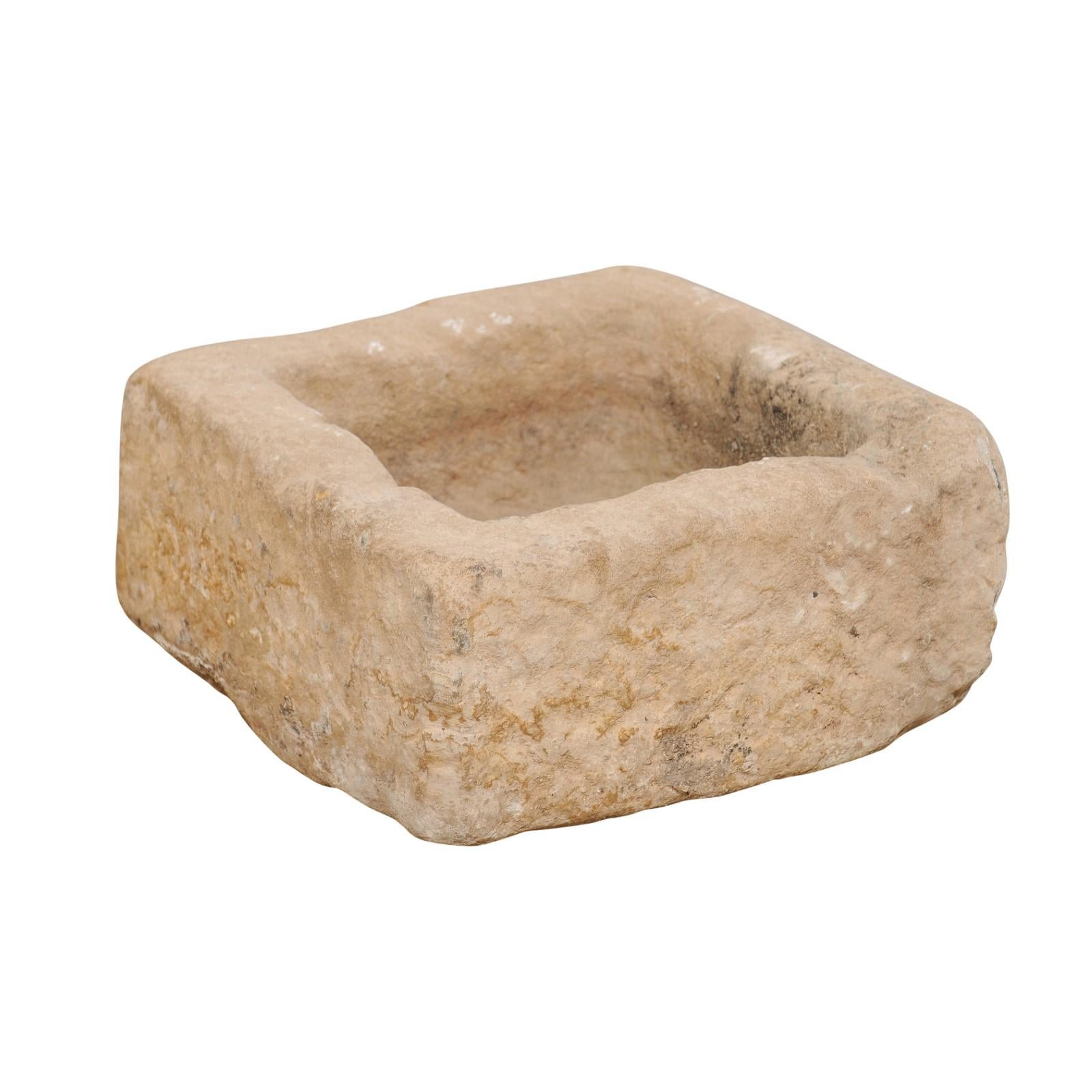 A Spanish carved stone trough from the 19th century. This smaller-sized antique trough from Spain, with its squared shape, has been hand carved out of a single piece of stone, having a nicely textured surface. In addition to standing alone as a