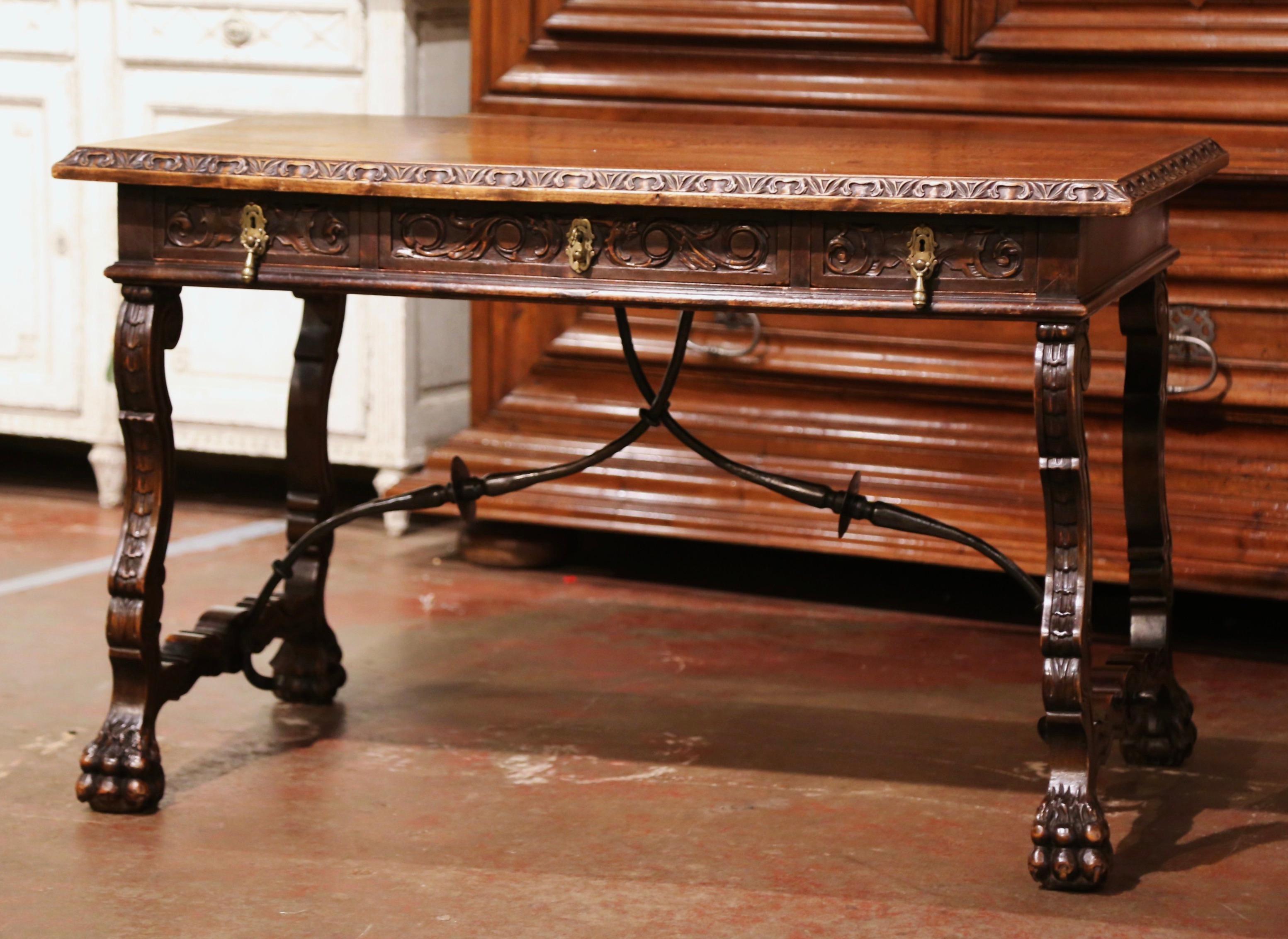 Add an elegant focal point to your study or library with this antique fruitwood desk. Carved in Spain circa 1880, the trestle table stands on two intricate carved legs ending with paw feet, and connected with a thick forged wrought iron stretcher.