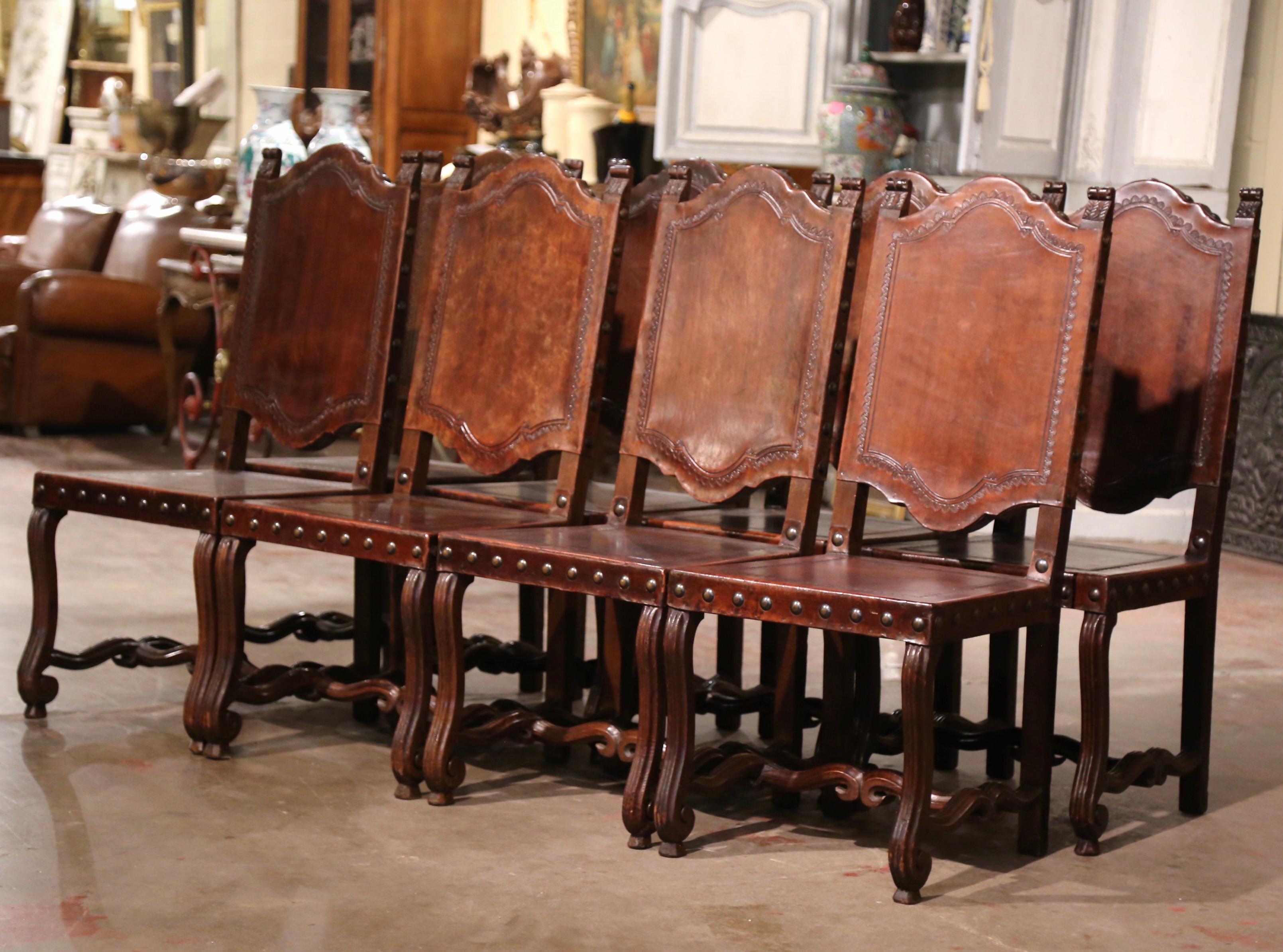 Dress a dining or breakfast table with this elegant suite of antique chairs. Crafted in Spain circa 1880, and built of walnut wood, each chair stands on carved and fluted legs ending with front scrolled legs; they are further decorated with a bottom