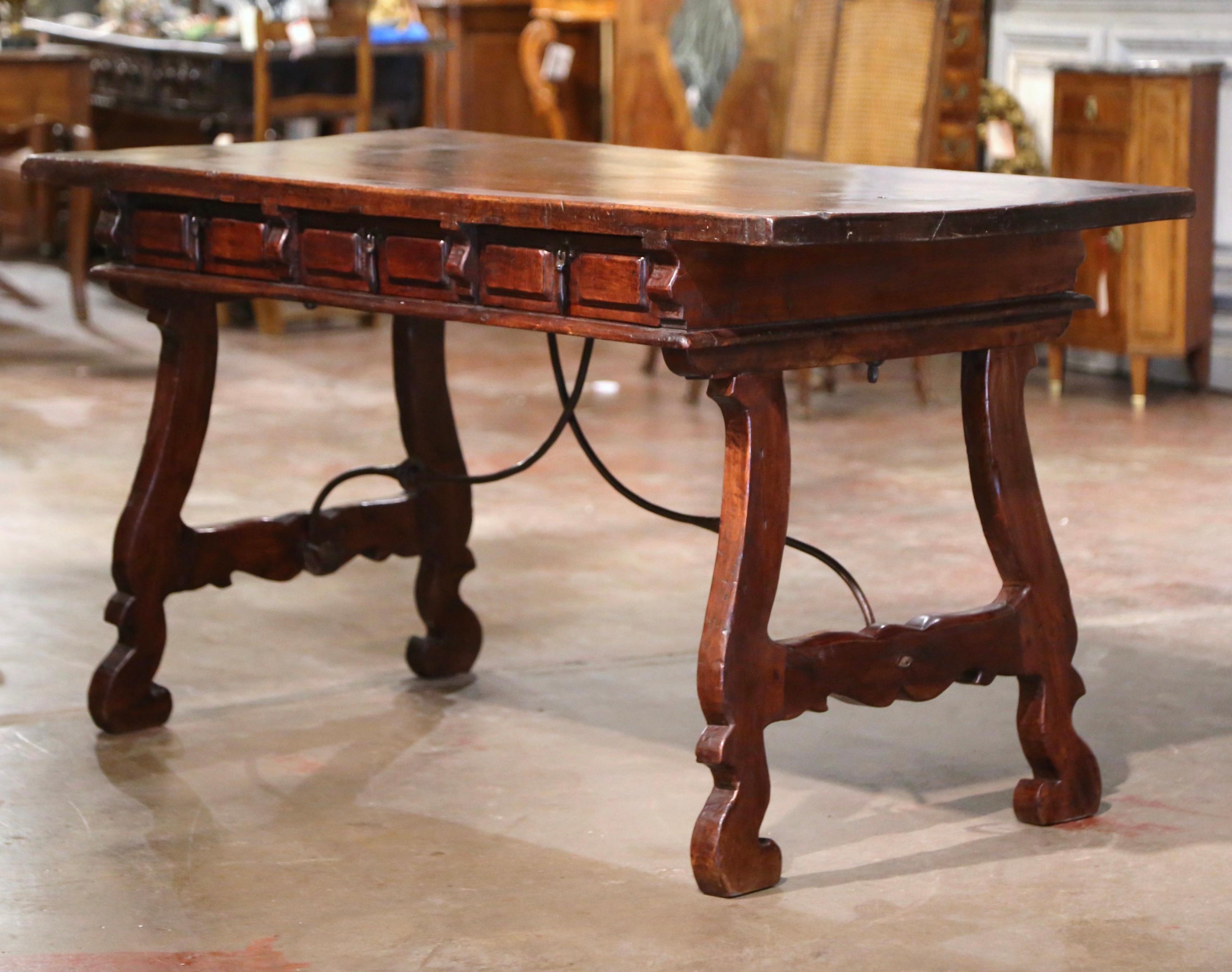 Add an elegant focal point to your study or library with this antique Spanish desk. Carved in Spain circa 1850, the trestle table stands on two intricate carved legs, connected with a thick, forged wrought iron stretcher. The top built with one