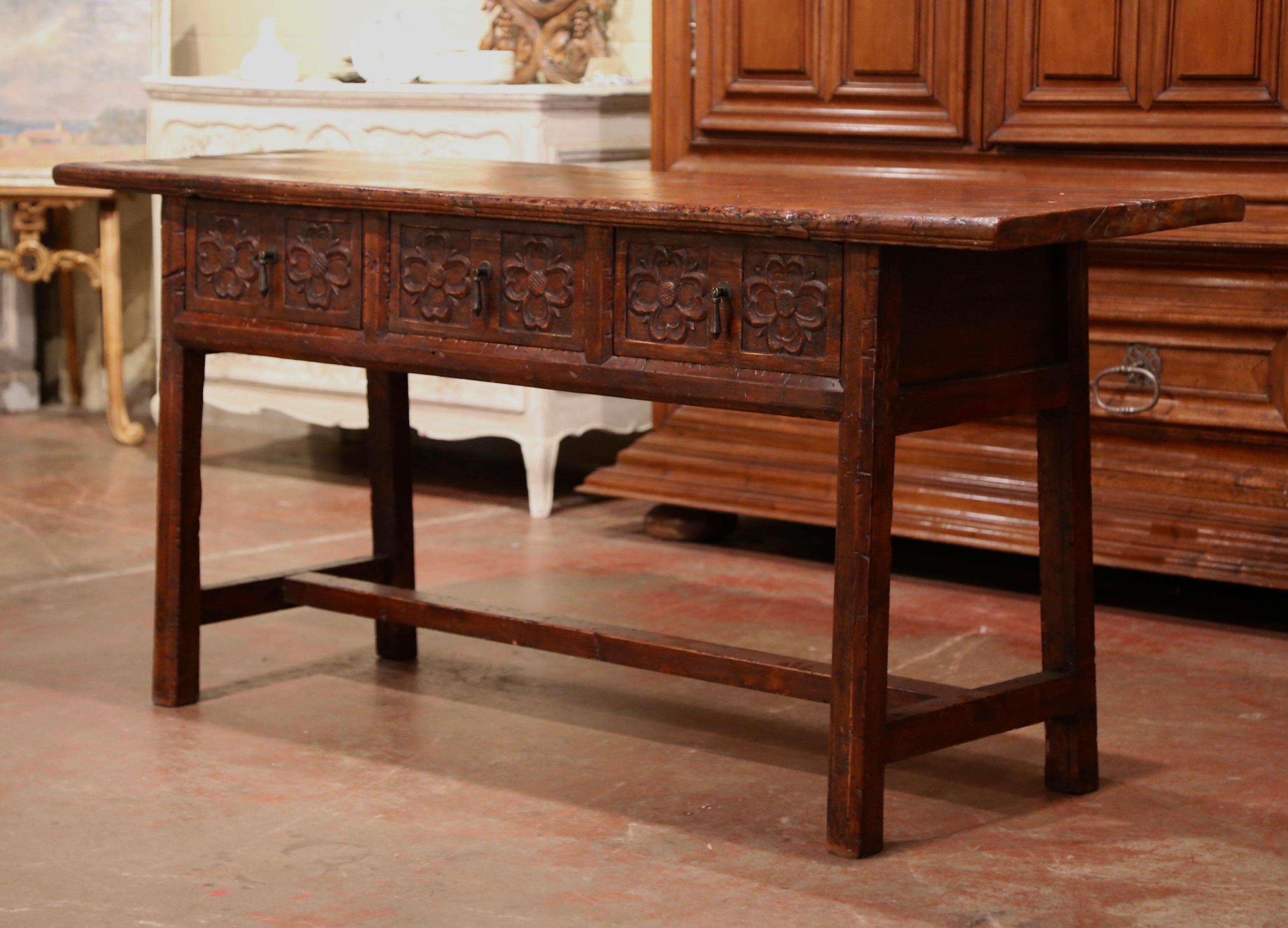 Place this elegant antique fruitwood console behind a sofa or against a wall; crafted in Spain, circa 1880, the long and narrow table stands on four straight legs ending with a bottom stretcher at the base. The piece features three heavily carved