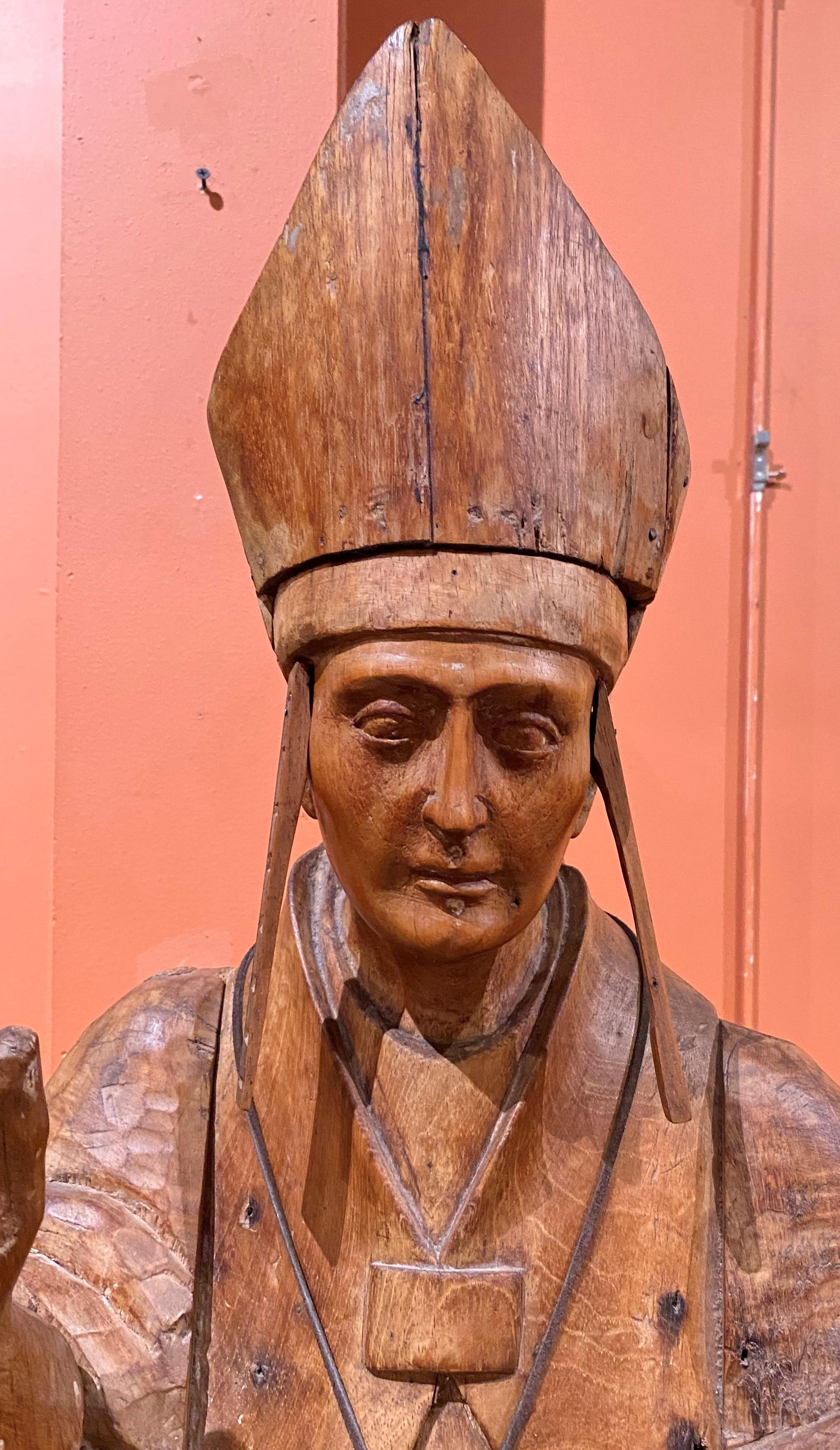 A nicely carved wooden Spanish Colonial bishop religious figure with mitre, robe, and metal crucifix hanging around his neck, dating to the 19th century. Possibly Guatemalan in origin. Very good overall condition, with nice surface patina, minor