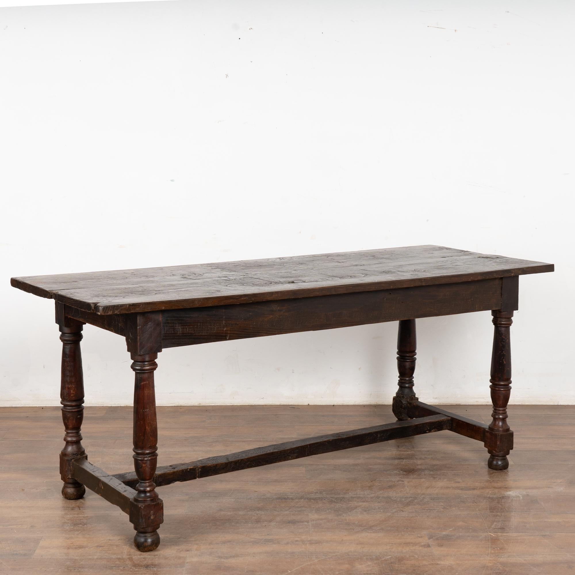 Table console ou bibliothèque en noyer foncé reposant sur des pieds tournés et un brancard. 
Veuillez agrandir les photos (en particulier celle du plateau) pour apprécier la patine foncée du bois, y compris les anciennes fissures, gouges, nœuds,