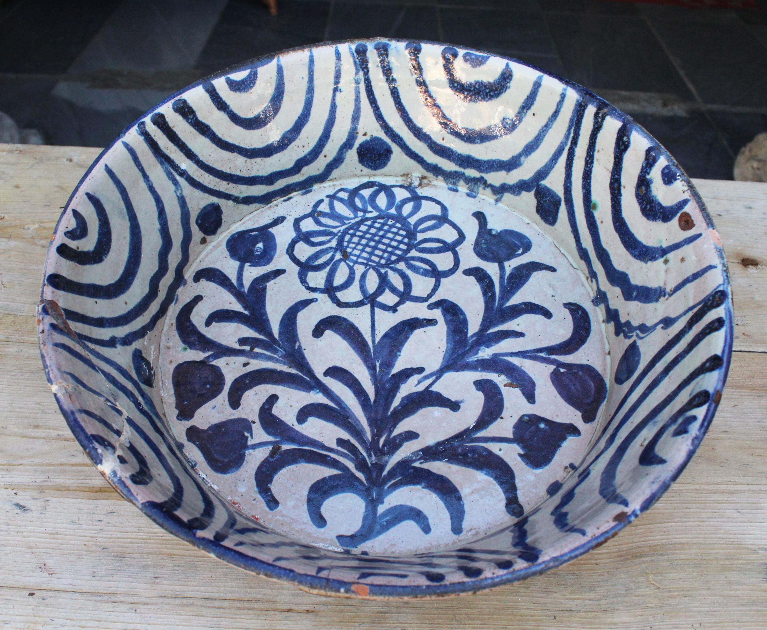 19th century Spanish Fajalauza white and blue glazed terracotta decorative plate painted with flowers. 

Fajalauza is a style that originates in Granada's Albaicín suburb, known for its mix of Christian and Al-Andalus cultures, as can be admired