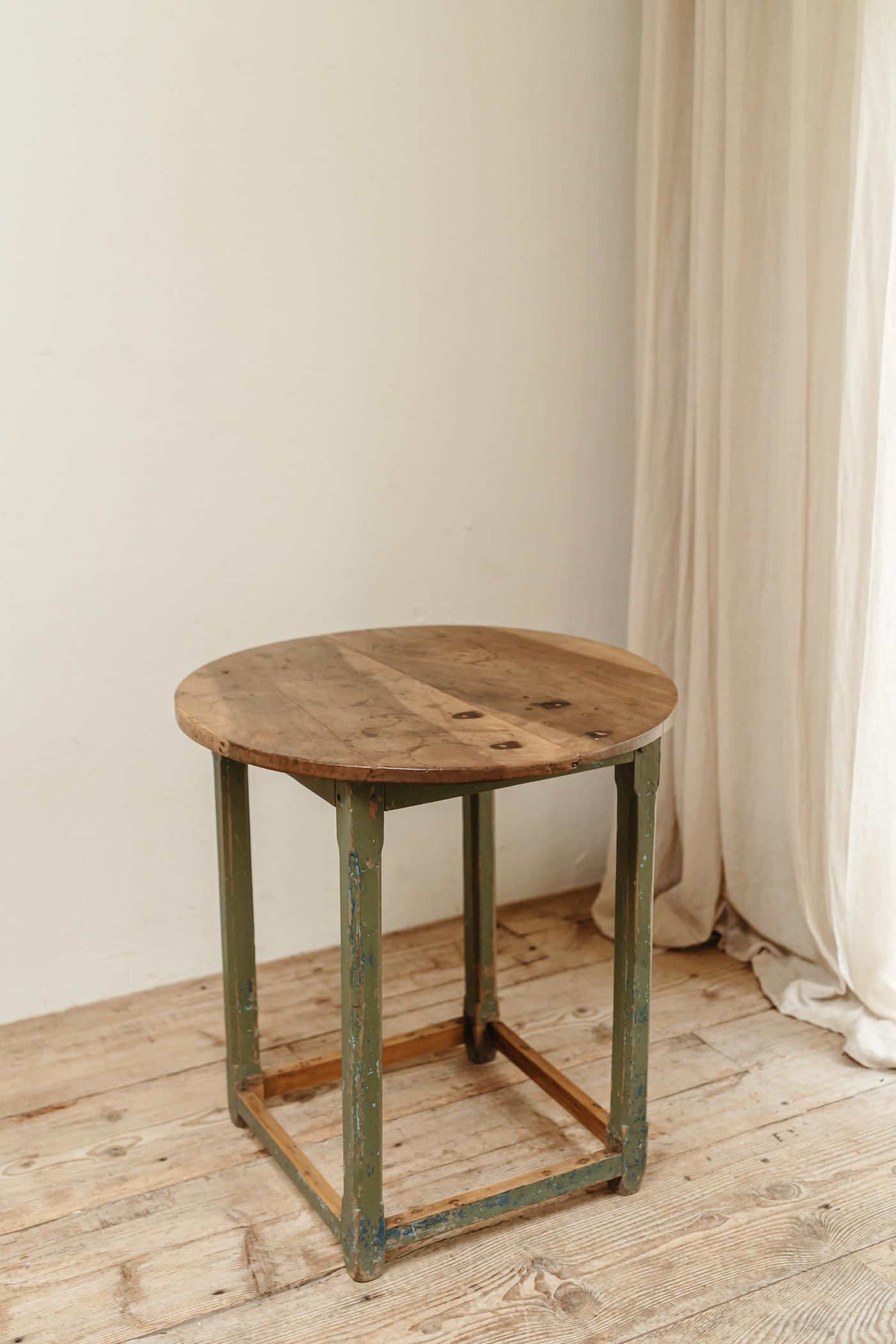 Une table à plateau en bois fruitier sur une base peinte en vert sapin, élégante et robuste,
en très bon état vintage.