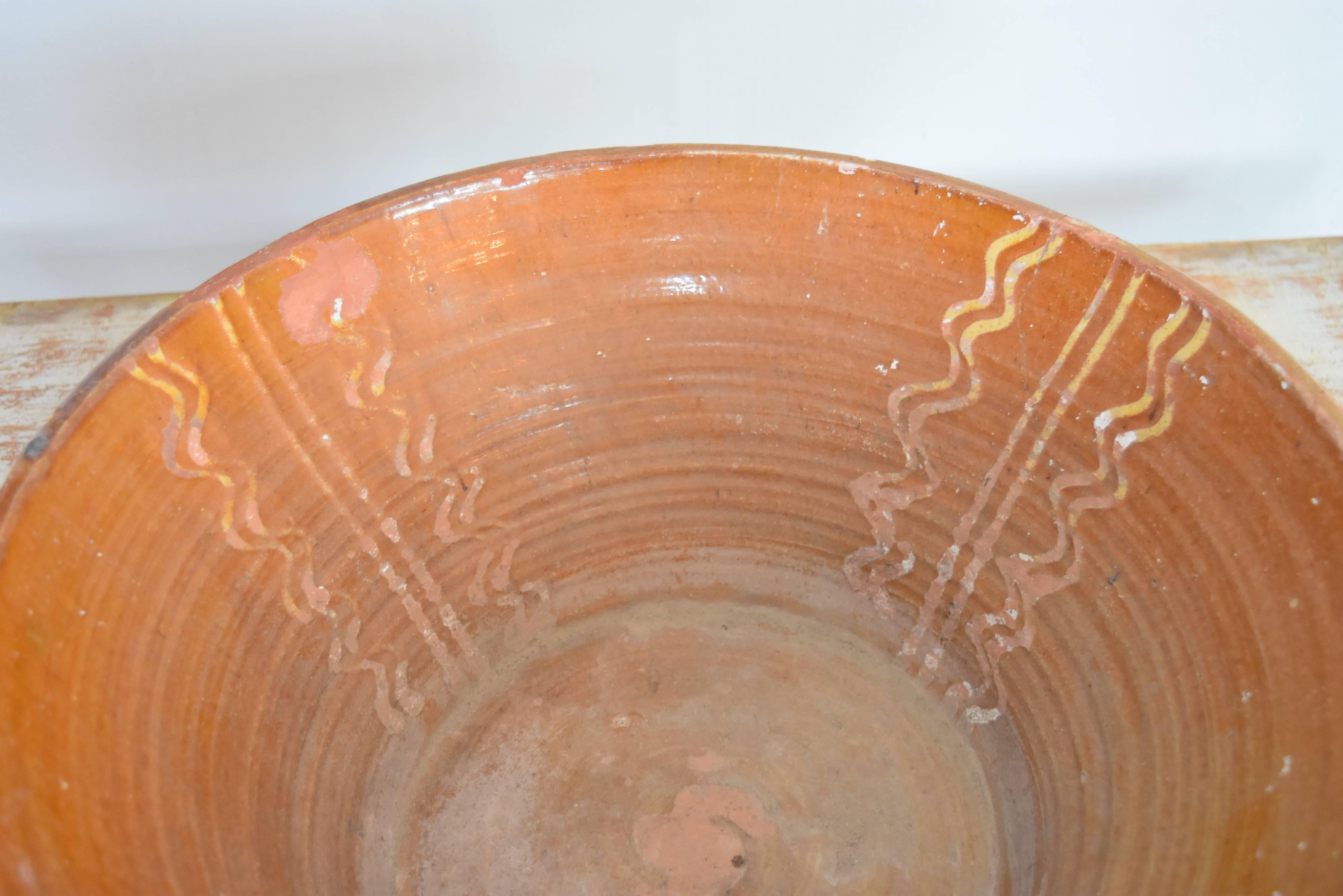 These bowls were used both as decor and in the kitchen. This one has a handsome patina with glazed earthy orange and squiggles of lemon glaze in the design. It comes from the Tarragona area of Spain.