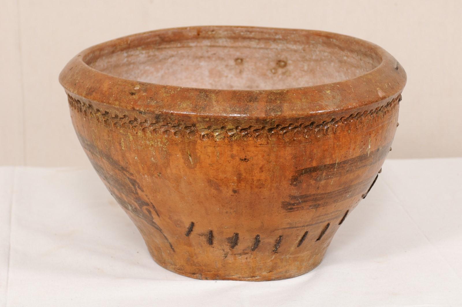 A Spanish clay pot with spout from the 19th century. This antique round-shaped vessel from Spain is wider towards it's top and mid-section, becoming more narrow towards it's bottom, with a single spout at one lower side, and resting upon a flattened