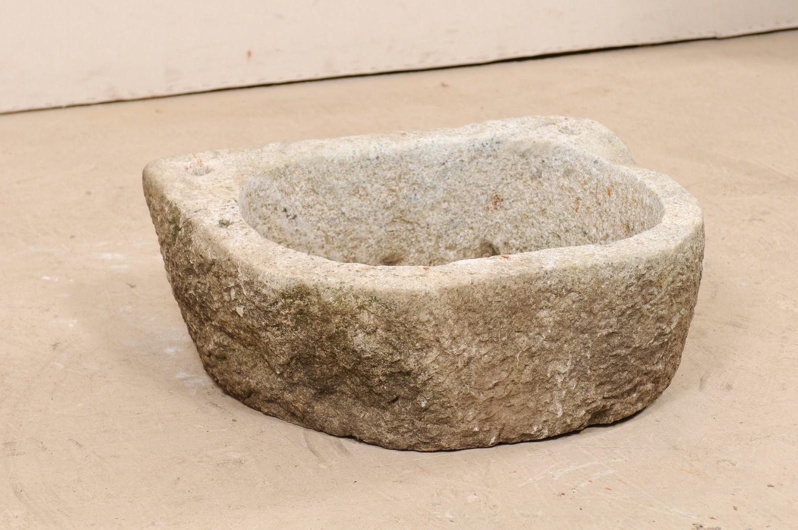 An antique Spanish carved stone trough or sink. This 19th century sink from Spain has a flattened backside with rounded square shaped body. It has been hand-carved from a single piece of stone, with wonderfully rustic texture. There are two holes,