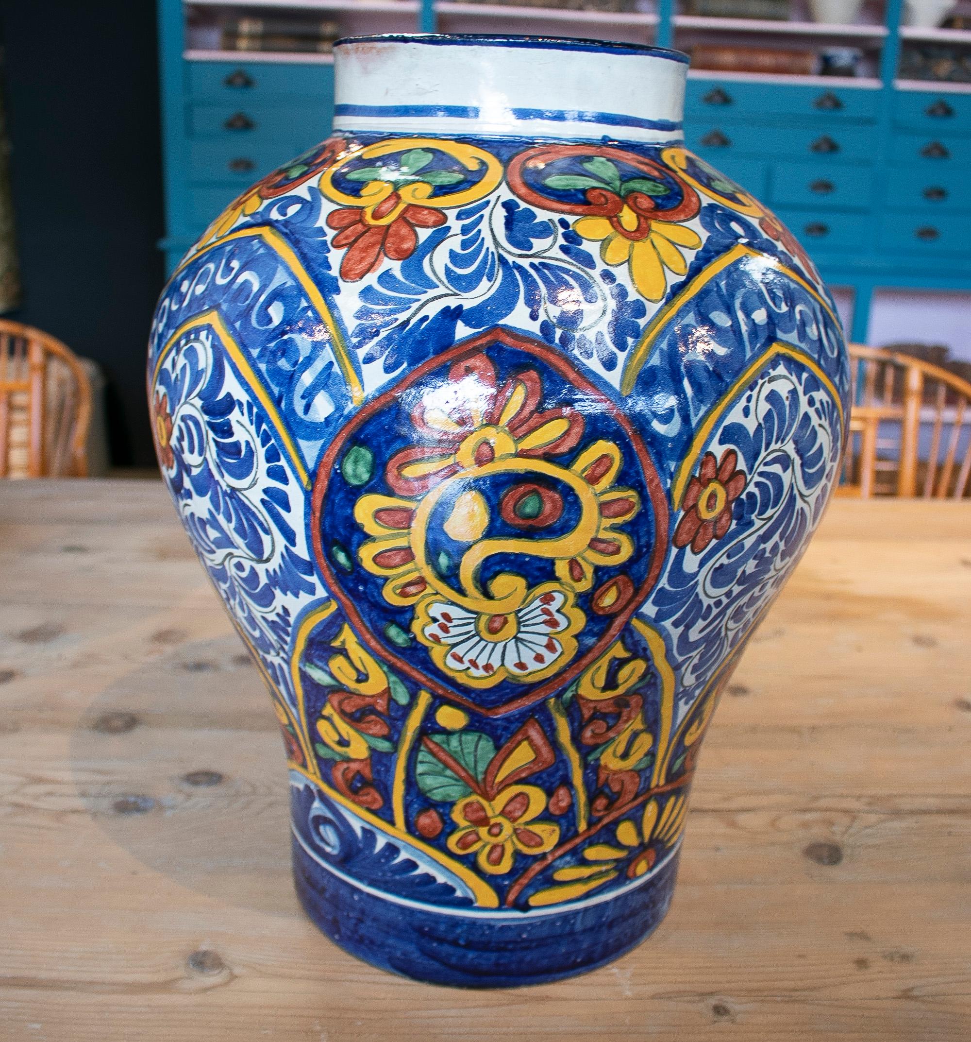 Antiguo jarrón de cerámica tradicional española del siglo XIX, hecho a mano, con motivos ornamentales inspirados en flores blancas, azules y amarillas. Firmado Alba H. Ennex.
  