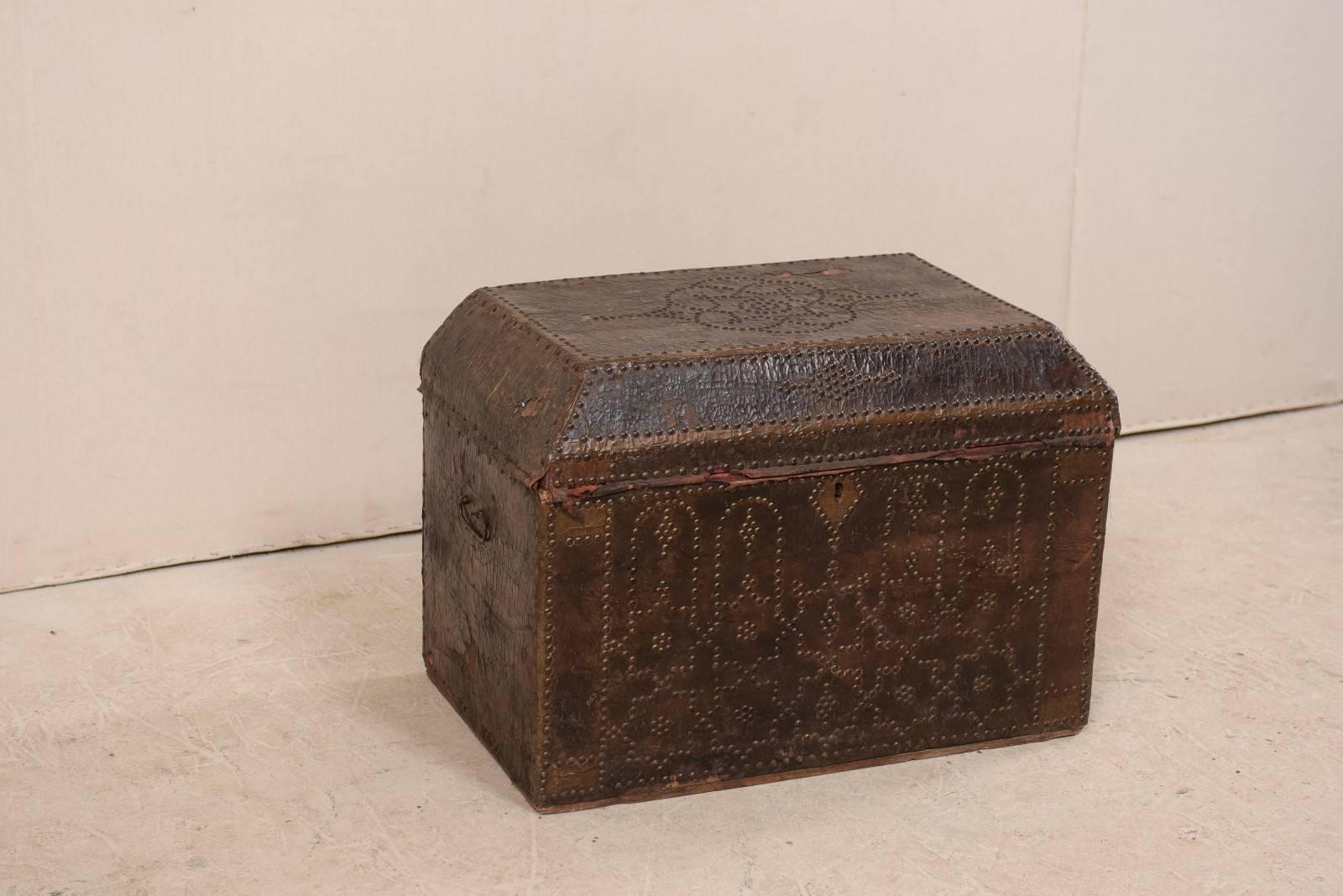 A 19th century Spanish colonial leather covered trunk. This antique Spanish coffer features a rectangular-domed top and is ornately decorated with brass studs, with special attention and patterned detail at the front and top. Some areas of leather