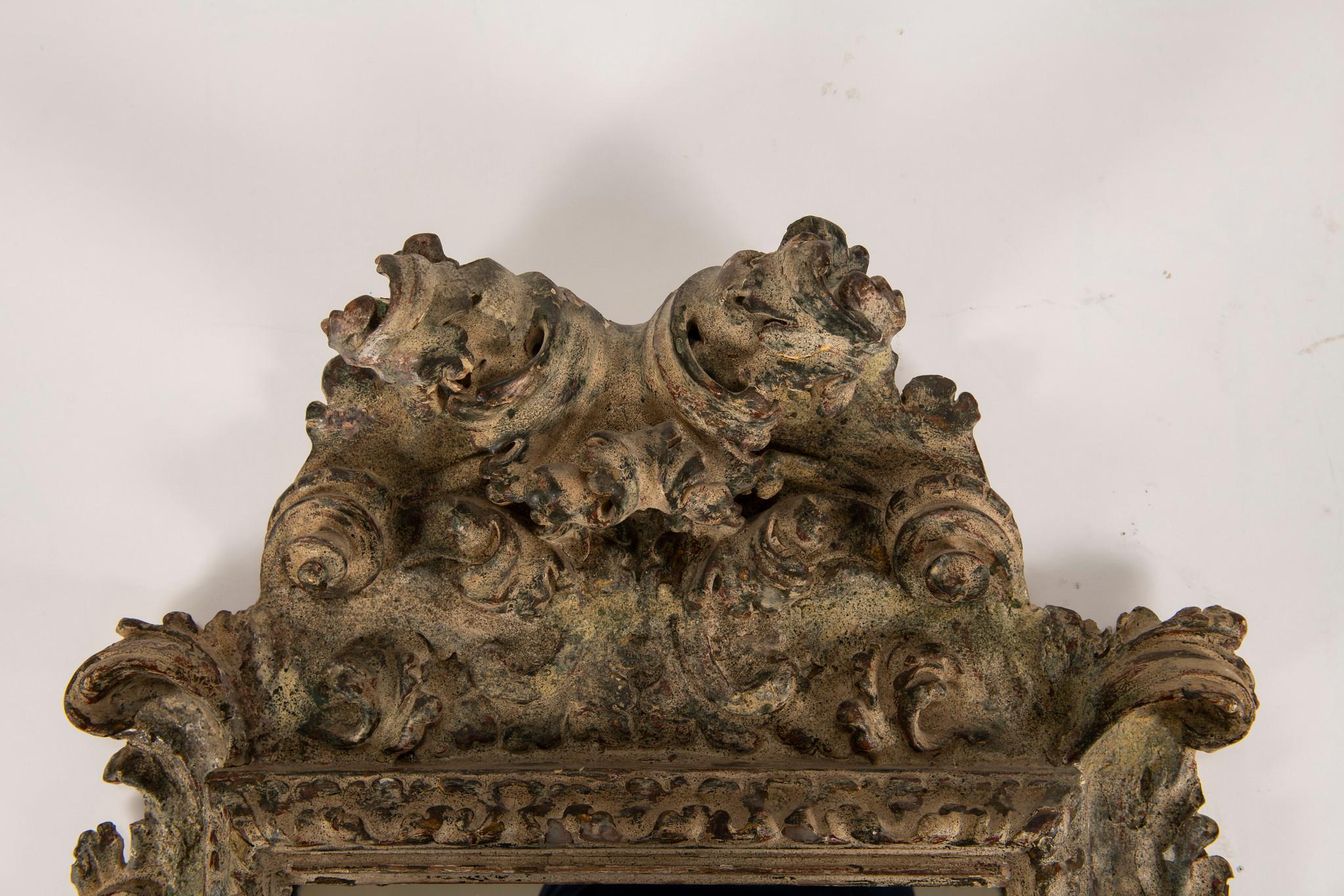 A beautiful ornately carved 19th century Spanish gesso mirror accented with flowers, scrolls and a large arching acanthus.
