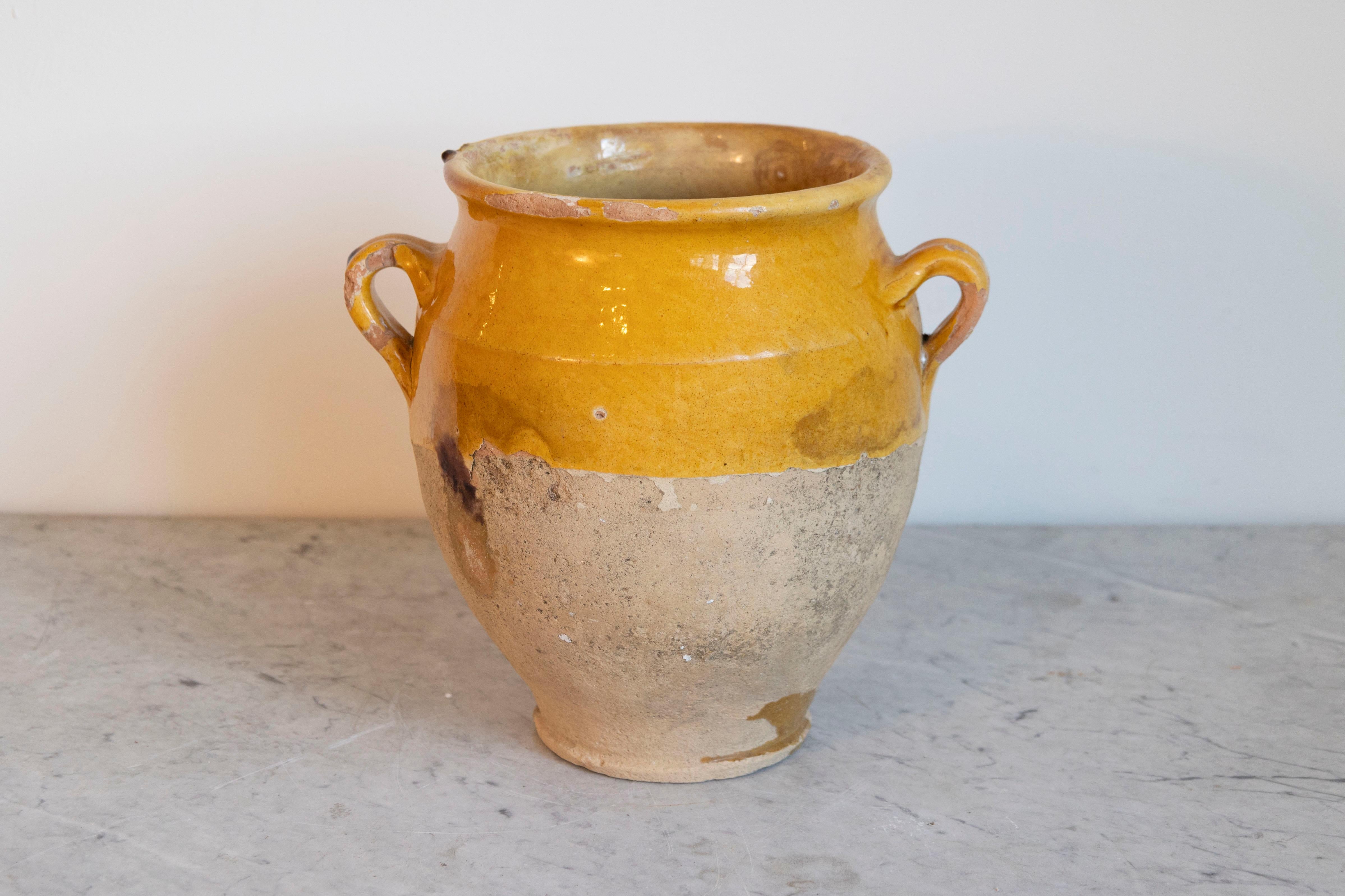 This 19th-century Spanish pottery jar is a beautiful example of rustic Mediterranean craftsmanship. Handcrafted from terracotta, the jar features a warm ochre glaze on the upper portion, contrasting with the unglazed, weathered base that highlights