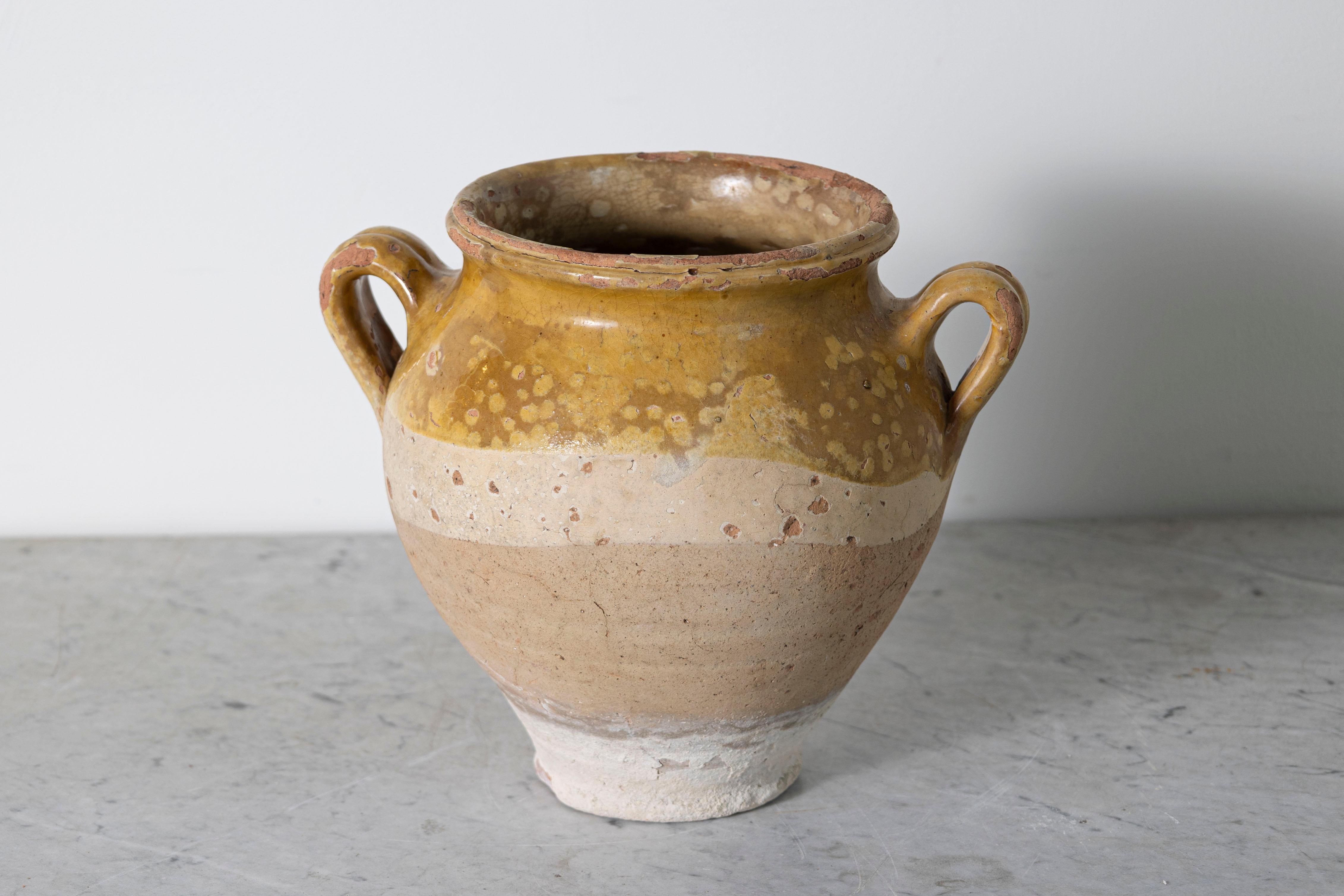 Questo vaso in terracotta spagnola del XIX secolo è un esempio di eleganza rustica e di artigianato tradizionale. Realizzata a mano in terracotta, la sua parte superiore smaltata di ocra presenta variazioni naturali, completate da una sezione