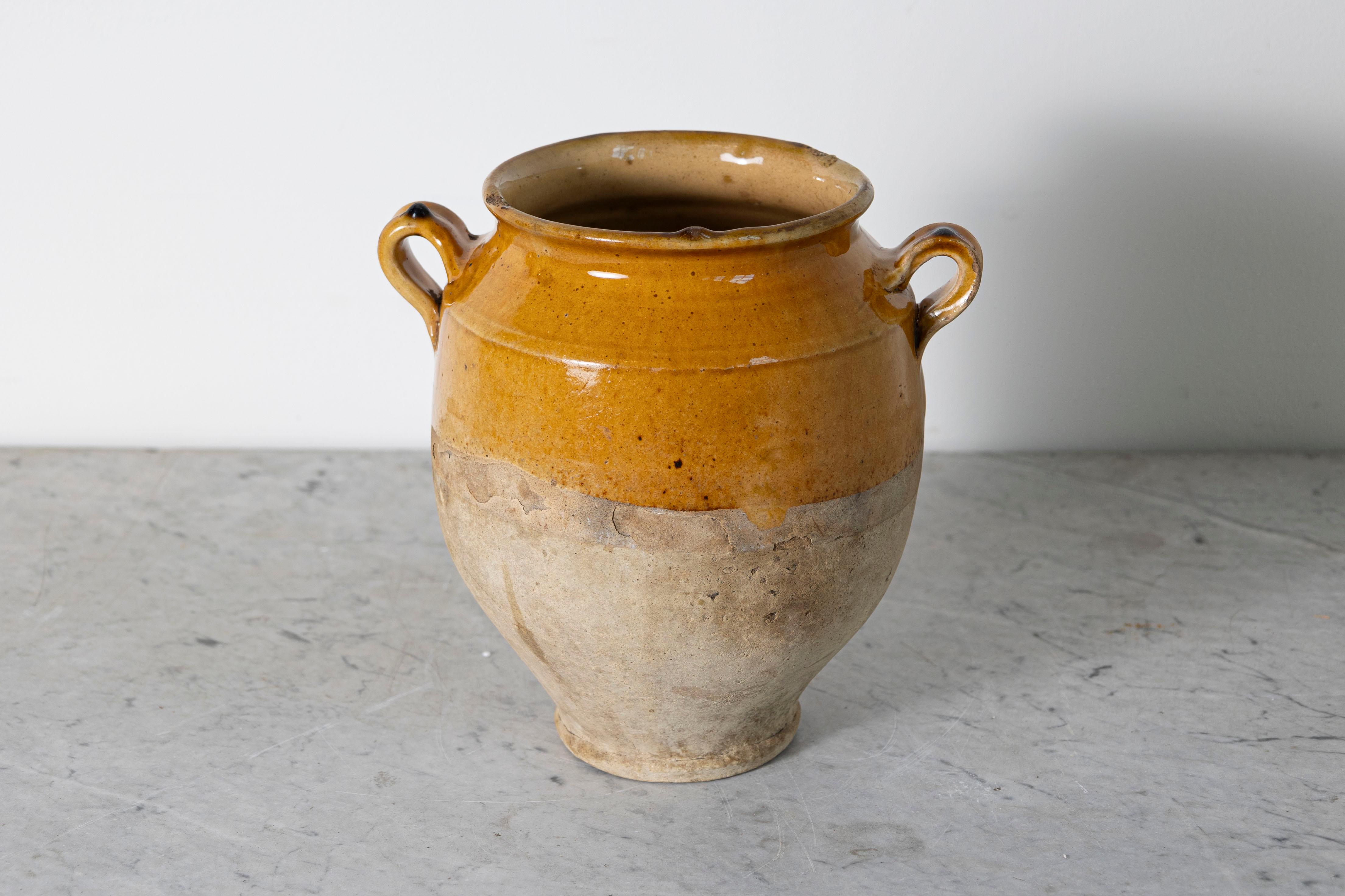 Questo vaso in ceramica spagnola del XIX secolo cattura magnificamente il fascino rustico e la maestria artigianale della regione mediterranea. Realizzato a mano in terracotta, presenta uno smalto ocra caldo sulla parte superiore che contrasta