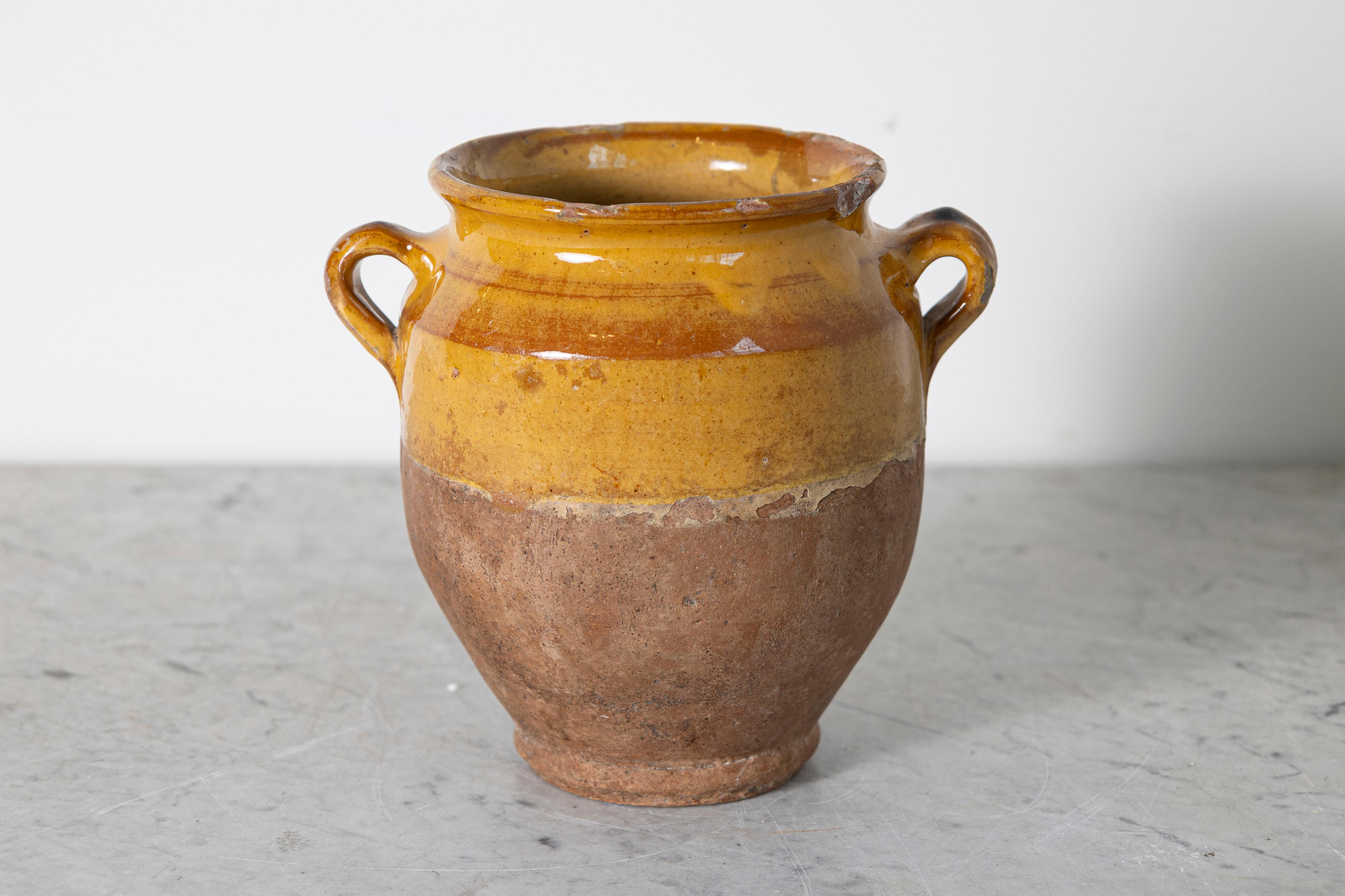 Questo vaso in ceramica spagnola del XIX secolo cattura magnificamente il fascino rustico e la maestria artigianale della regione mediterranea. Realizzato a mano in terracotta, presenta uno smalto ocra caldo sulla parte superiore che contrasta