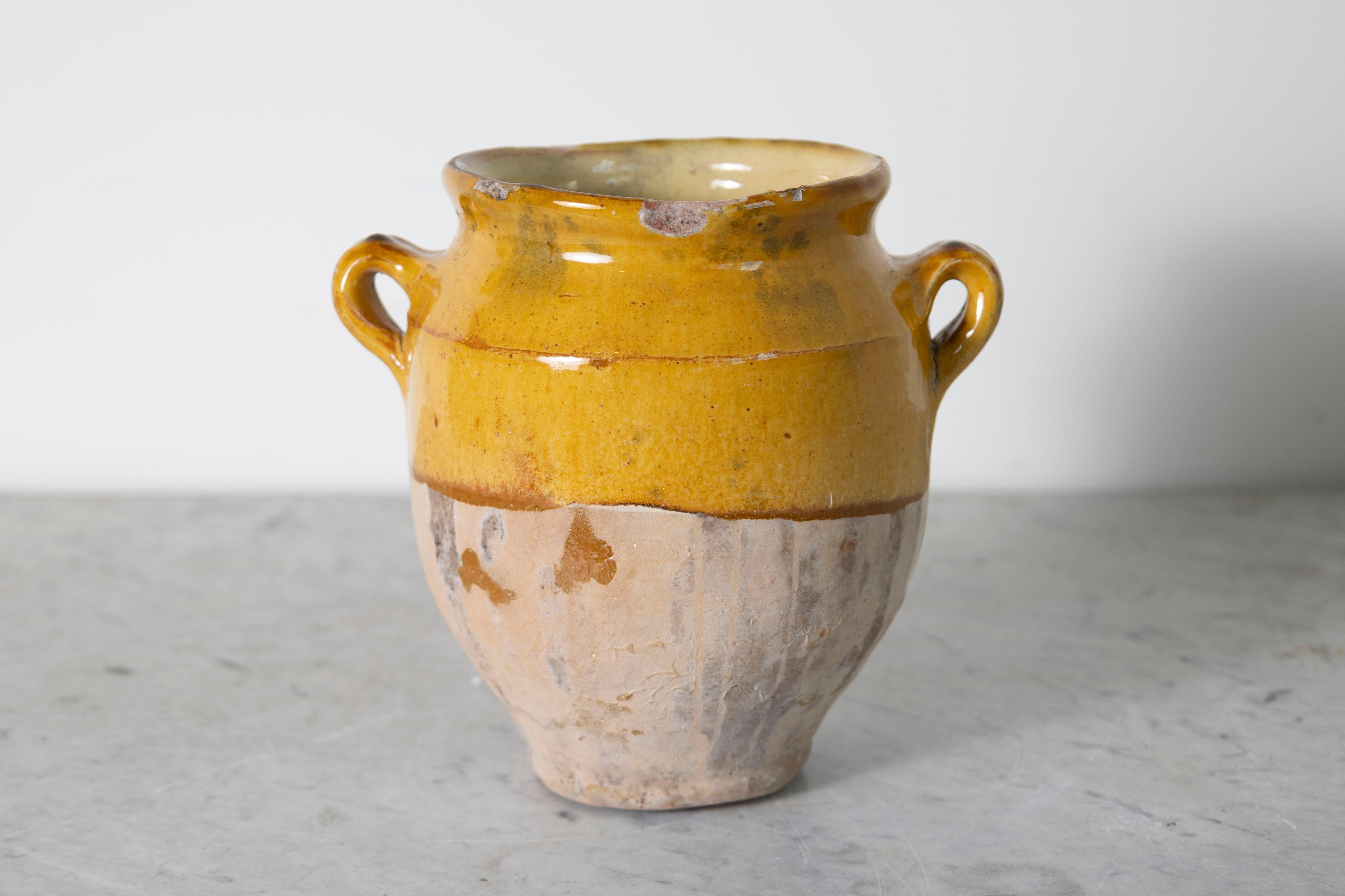 Cette jarre en poterie espagnole du XIXe siècle est un bel exemple de l'artisanat méditerranéen rustique. Fabriquée à la main en terre cuite, la jarre présente une glaçure ocre chaude sur la partie supérieure, contrastant avec la base non glacée et