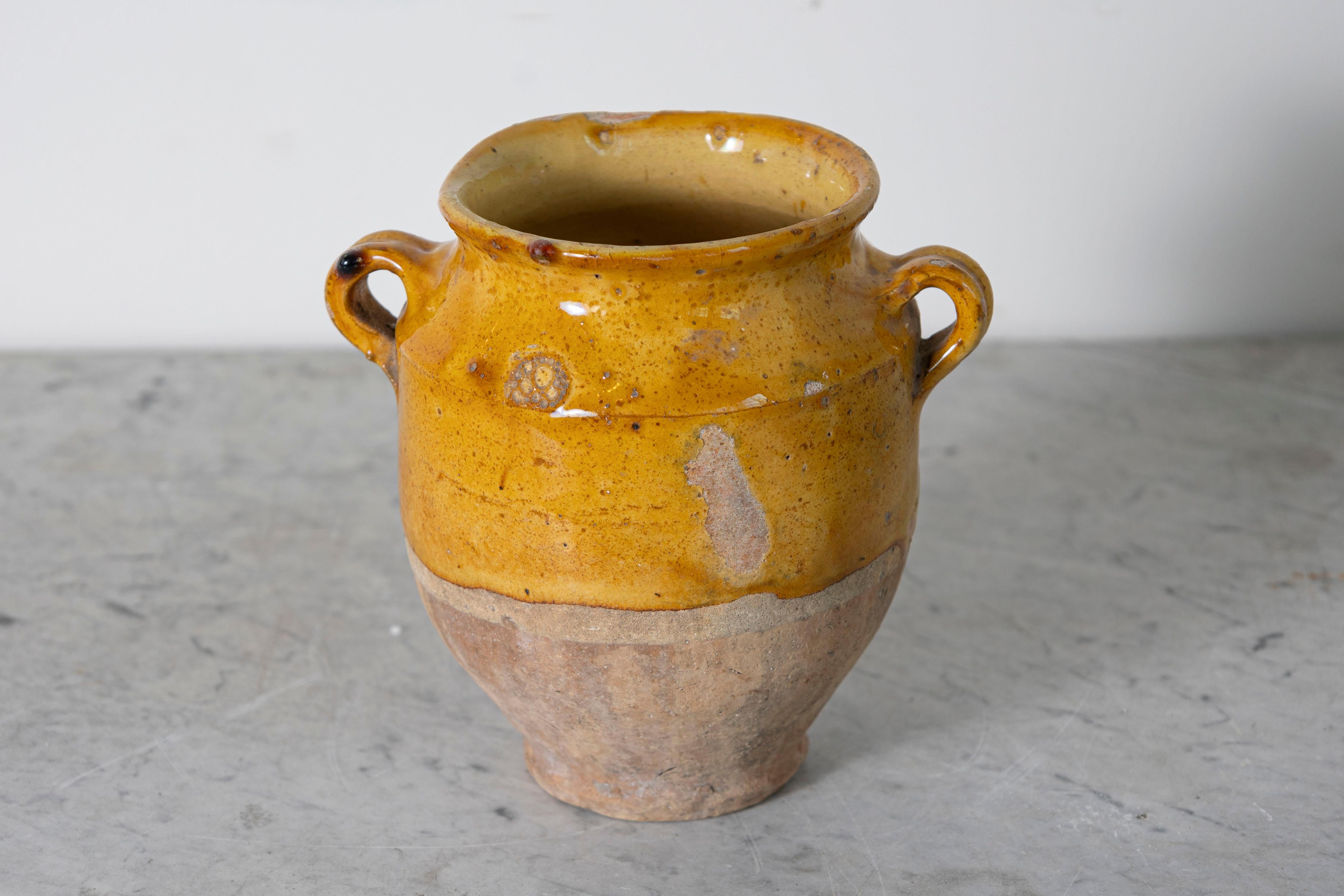 Questo vaso di ceramica spagnolo del XIX secolo è un bellissimo esempio di artigianato mediterraneo rustico. Realizzato a mano in terracotta, l'orcio presenta uno smalto ocra caldo sulla parte superiore, in contrasto con la base non smaltata e