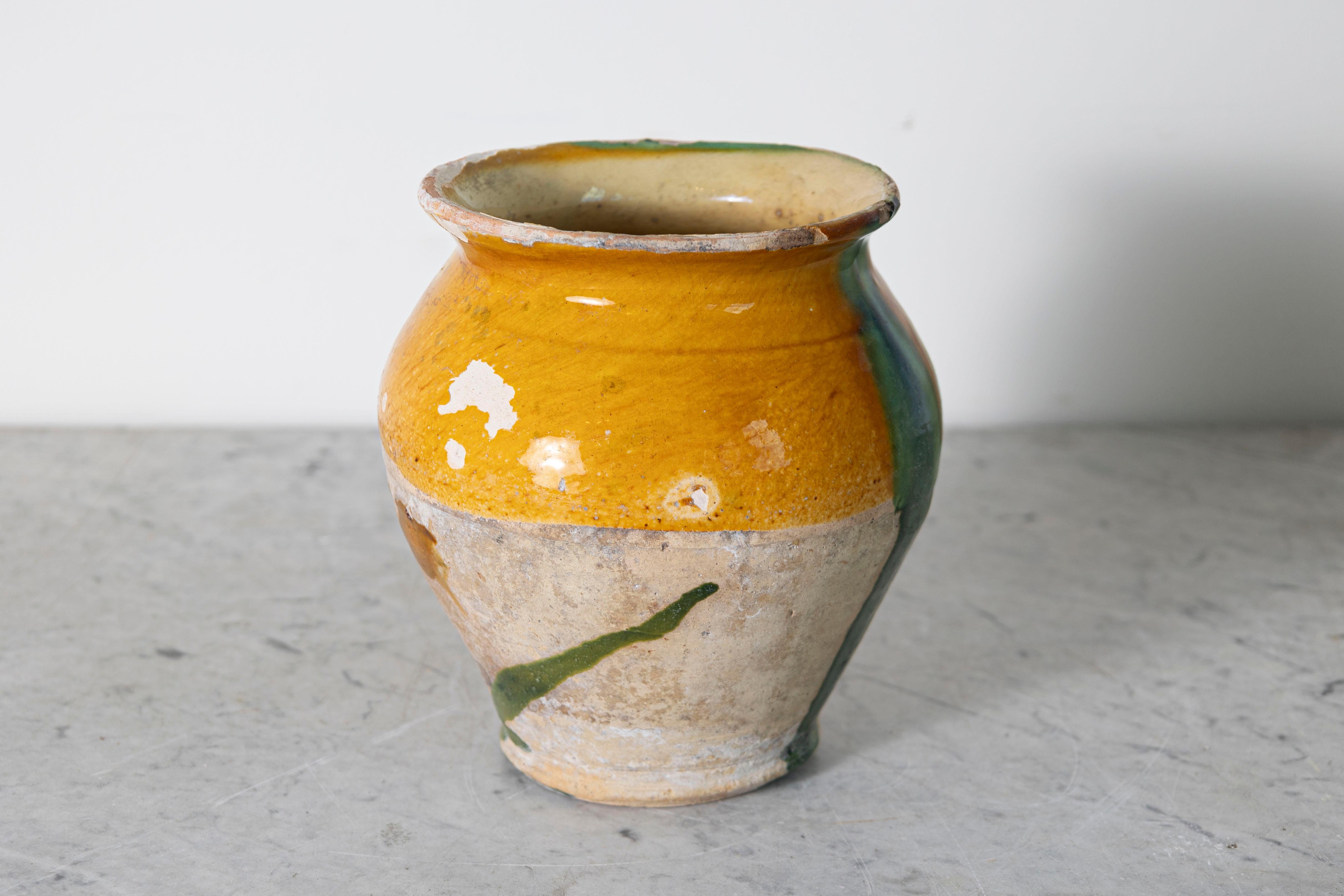 Questo vaso in ceramica spagnola del XIX secolo mostra il fascino rustico e l'estro artistico dell'artigianato tradizionale mediterraneo. Realizzato a mano in terracotta, il suo caldo smalto ocra è splendidamente accentuato da una vibrante goccia