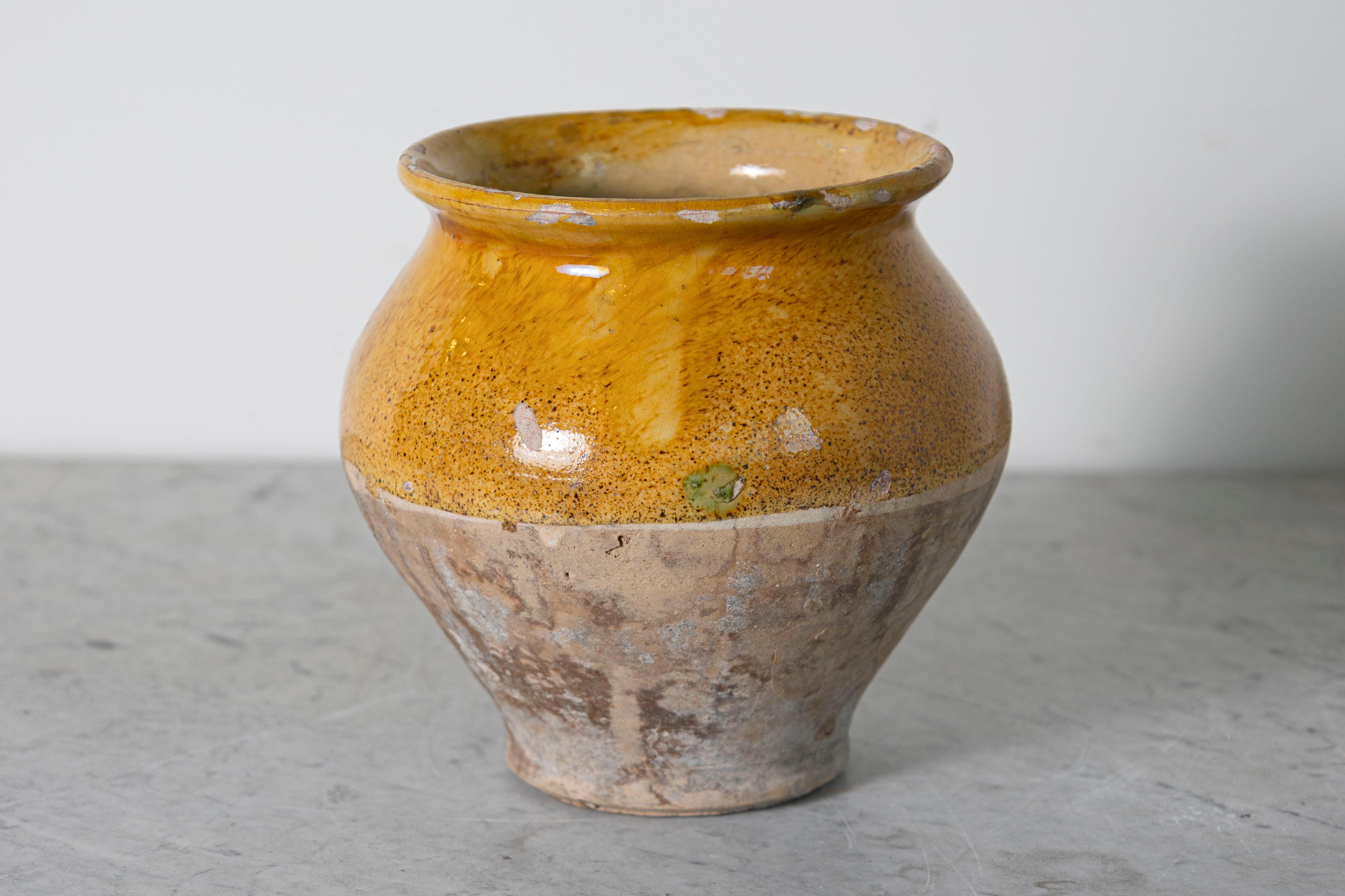 Questo vaso spagnolo in terracotta smaltata del XIX secolo è un delizioso esempio di artigianato mediterraneo rustico. La sua forma lavorata a mano mostra un caldo smalto ocra sulla metà superiore, splendidamente contrastato dalla base non smaltata