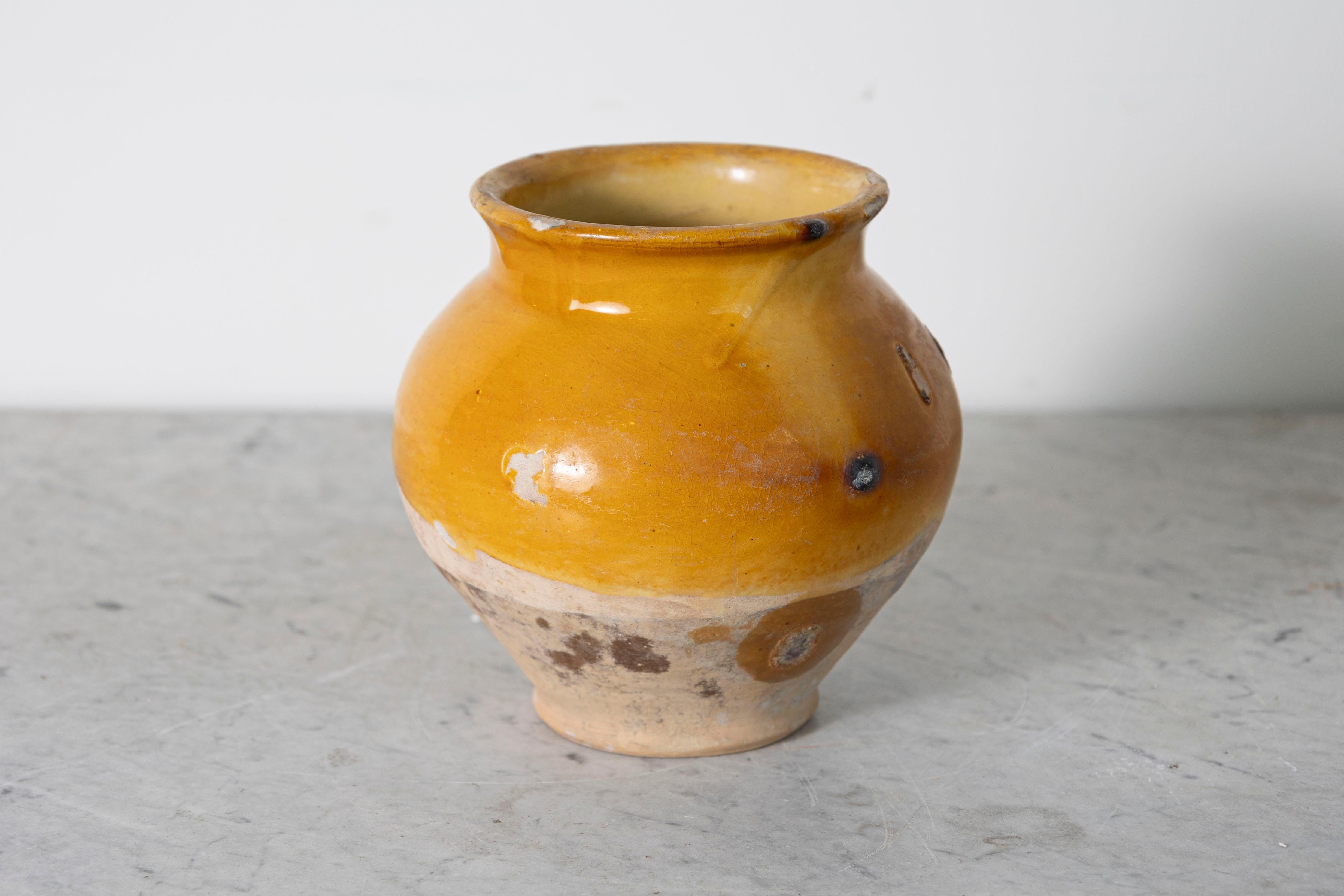 Questo vaso spagnolo in terracotta smaltata del XIX secolo è un delizioso esempio di artigianato mediterraneo rustico. La sua forma lavorata a mano mostra un caldo smalto ocra sulla metà superiore, splendidamente contrastato dalla base non smaltata