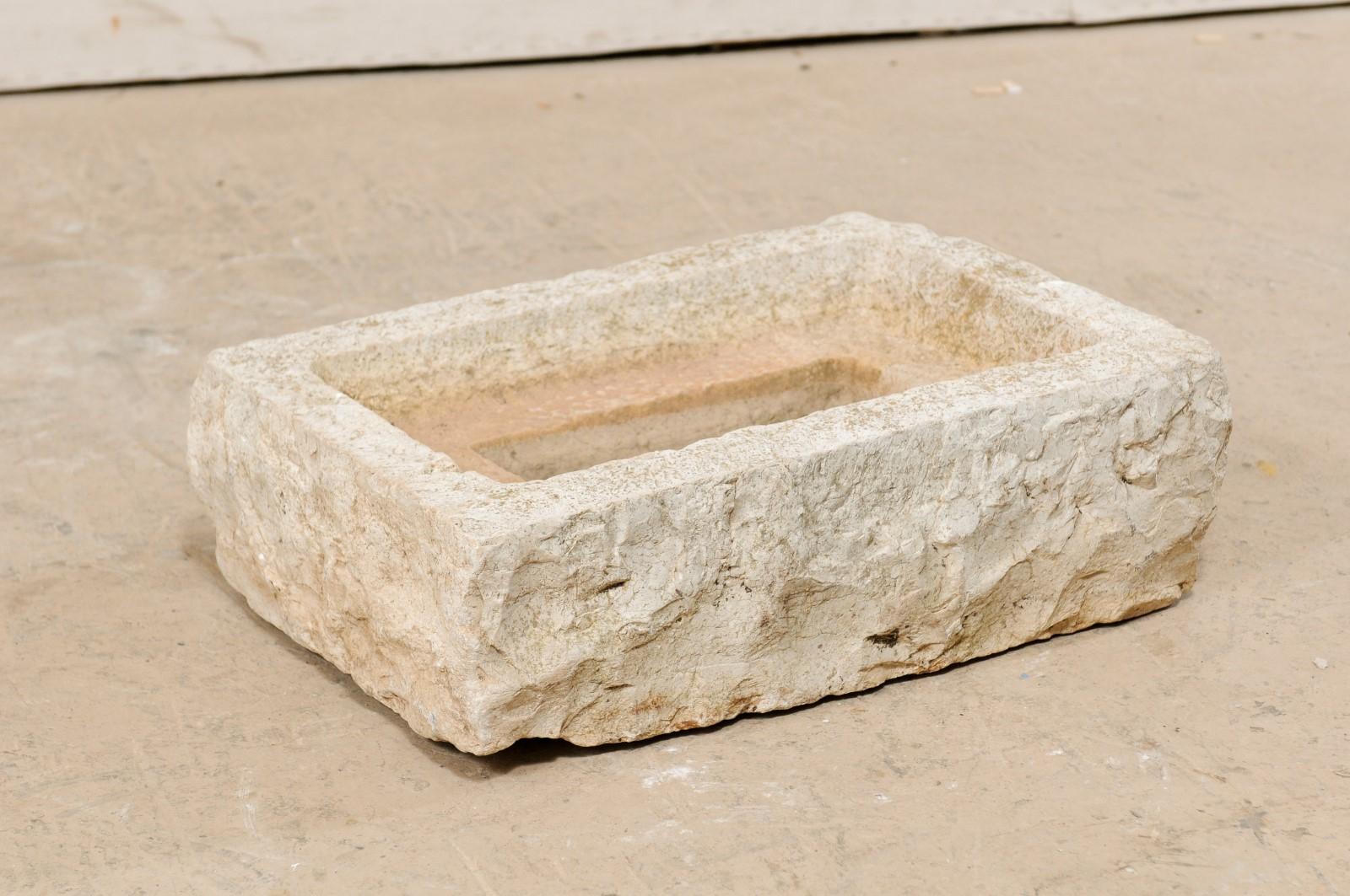 A Spanish carved stone trough from the 19th century. This antique trough from Spain, with it's rectangular shape, has been hand carved out of a single piece of stone, having a nicely textured surface and step-down basin within. In addition to