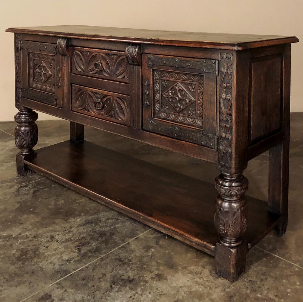 19th century Spanish Renaissance Credenza features a raised cabinet that is defined by extensive hand-carving across the facade, framed by carved cornerposts and a pair of carved corbels flanking the center drawer section. Geometric foliates are