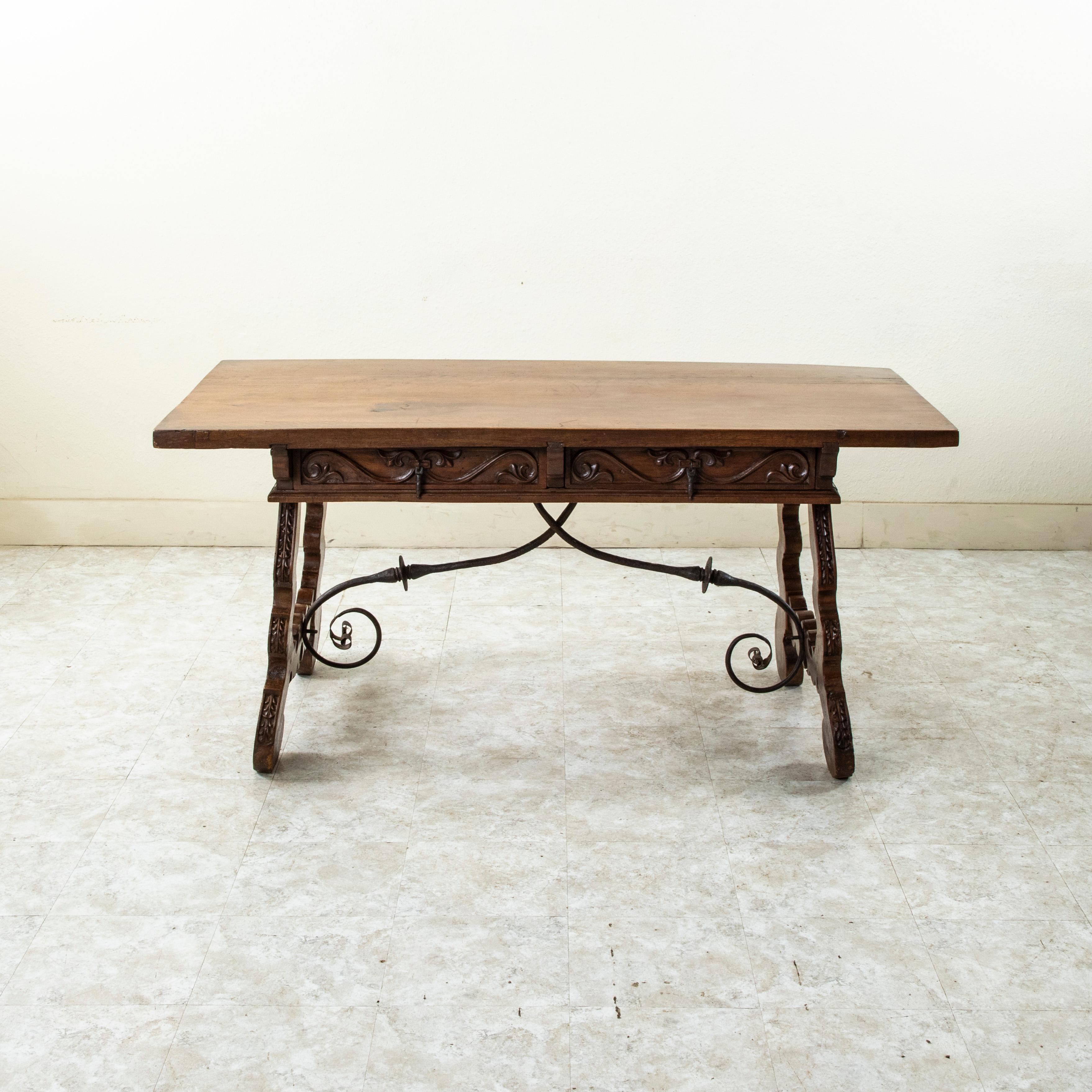 This mid nineteenth century Spanish Renaissance style walnut console table or writing table is double faced and features hand carved details on both sides. The top is constructed of two planks of wood and joins the base by means of three long