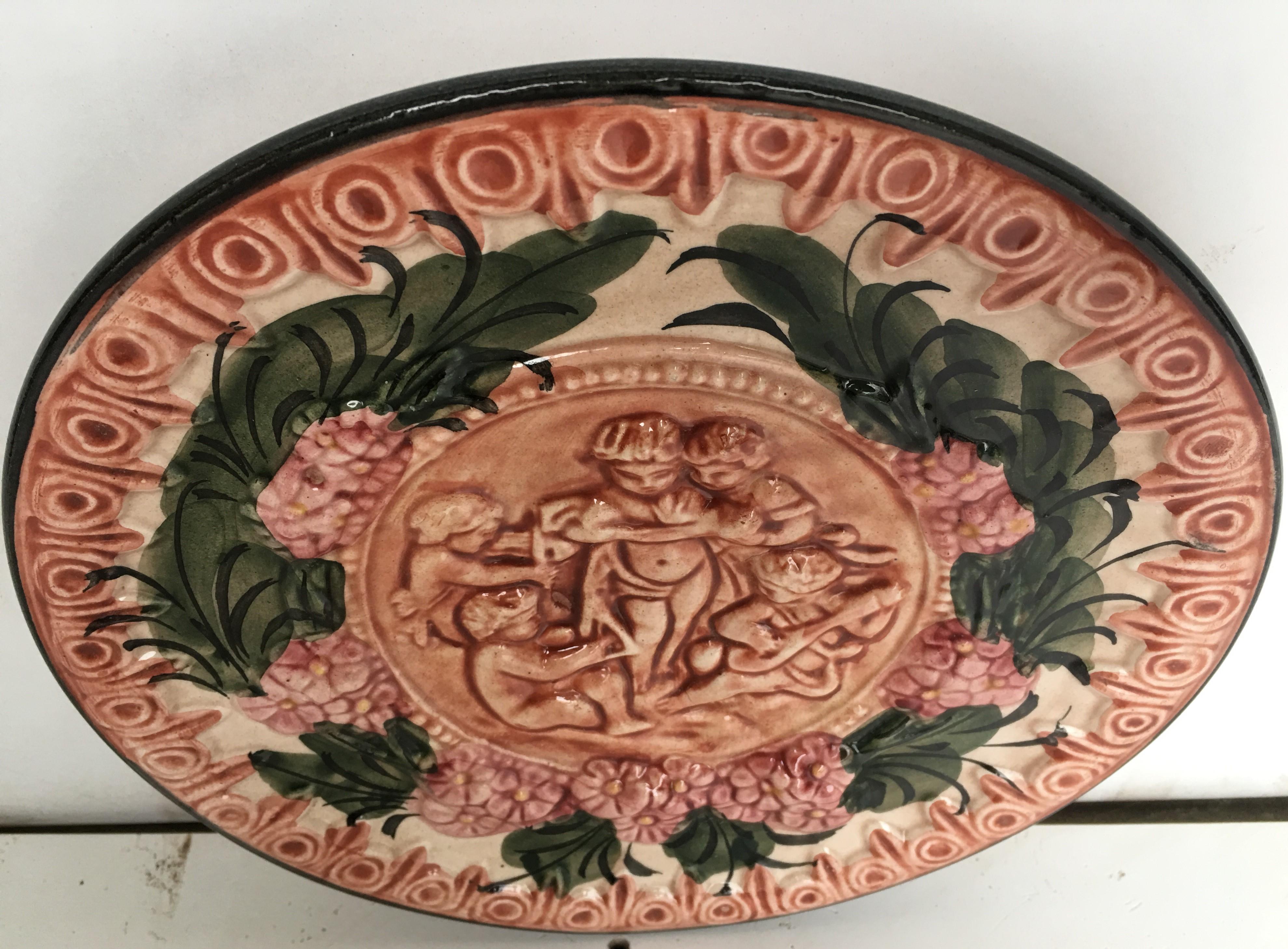 Lovely antique circular decorative terracotta dish, a round thick metal sheet centered by hand repoussé children figures playing, with flowers and superlative bas relief hand chased allegorical grottesques, scrolls and flowers on the round border.
 