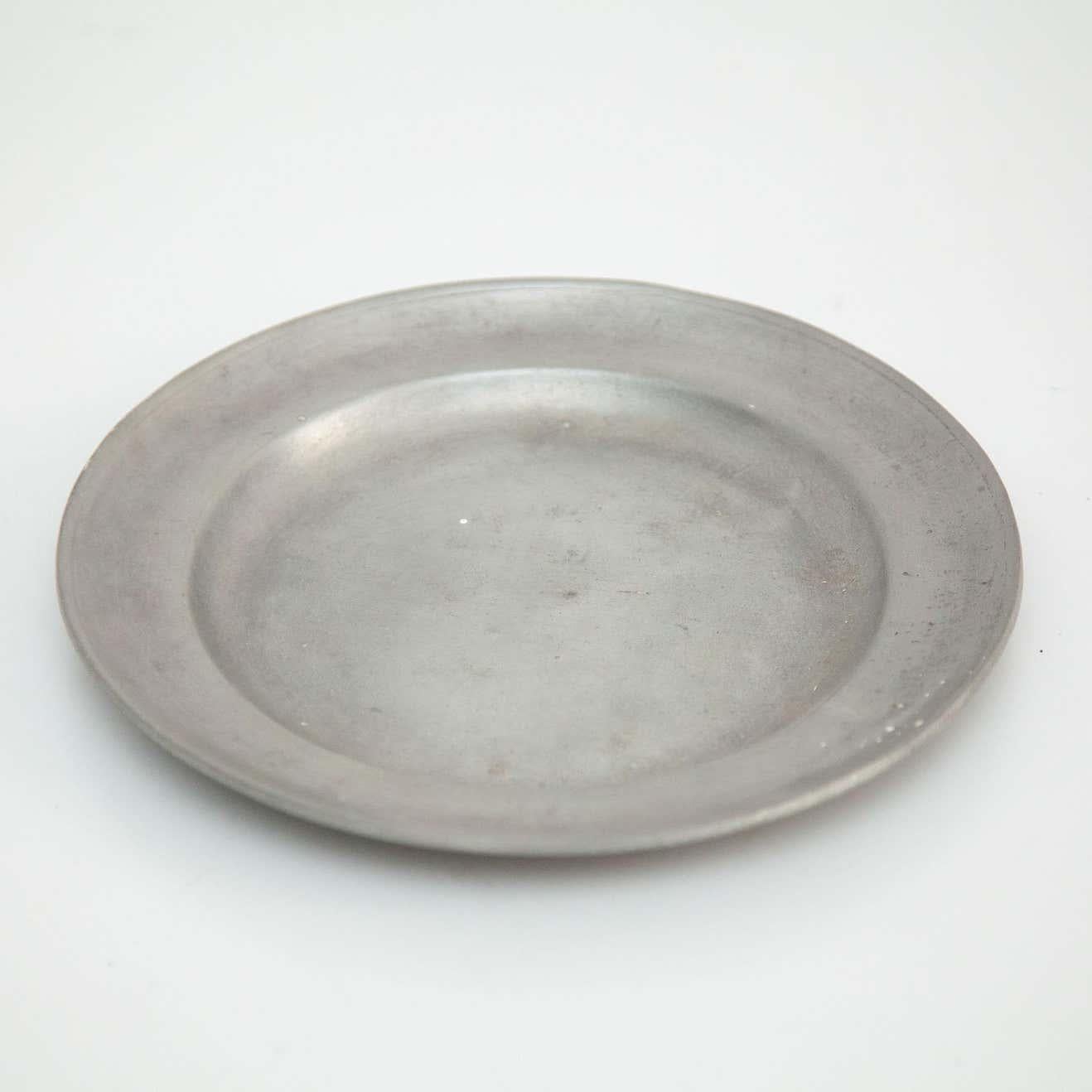 Piastra in metallo proveniente dalla Spagna di produttore ignoto, circa 19° secolo.    In condizioni originali, con lievi usure dovute all'età e all'uso, che conservano una bella patina.    Materiale:  Metallo    Dimensioni:  Ø 21 cm x H. 2 cm.