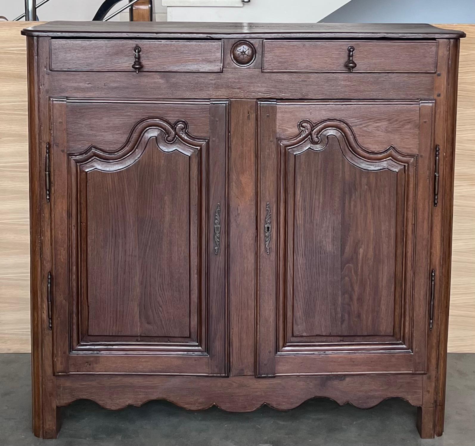 Buffet français à deux portes en noyer du début du 19e siècle. Cette armoire ancienne de France présente un plateau rectangulaire aux bords biseautés, au-dessus d'un caisson abritant une paire de portes à panneaux joliment sculptés, flanqués de