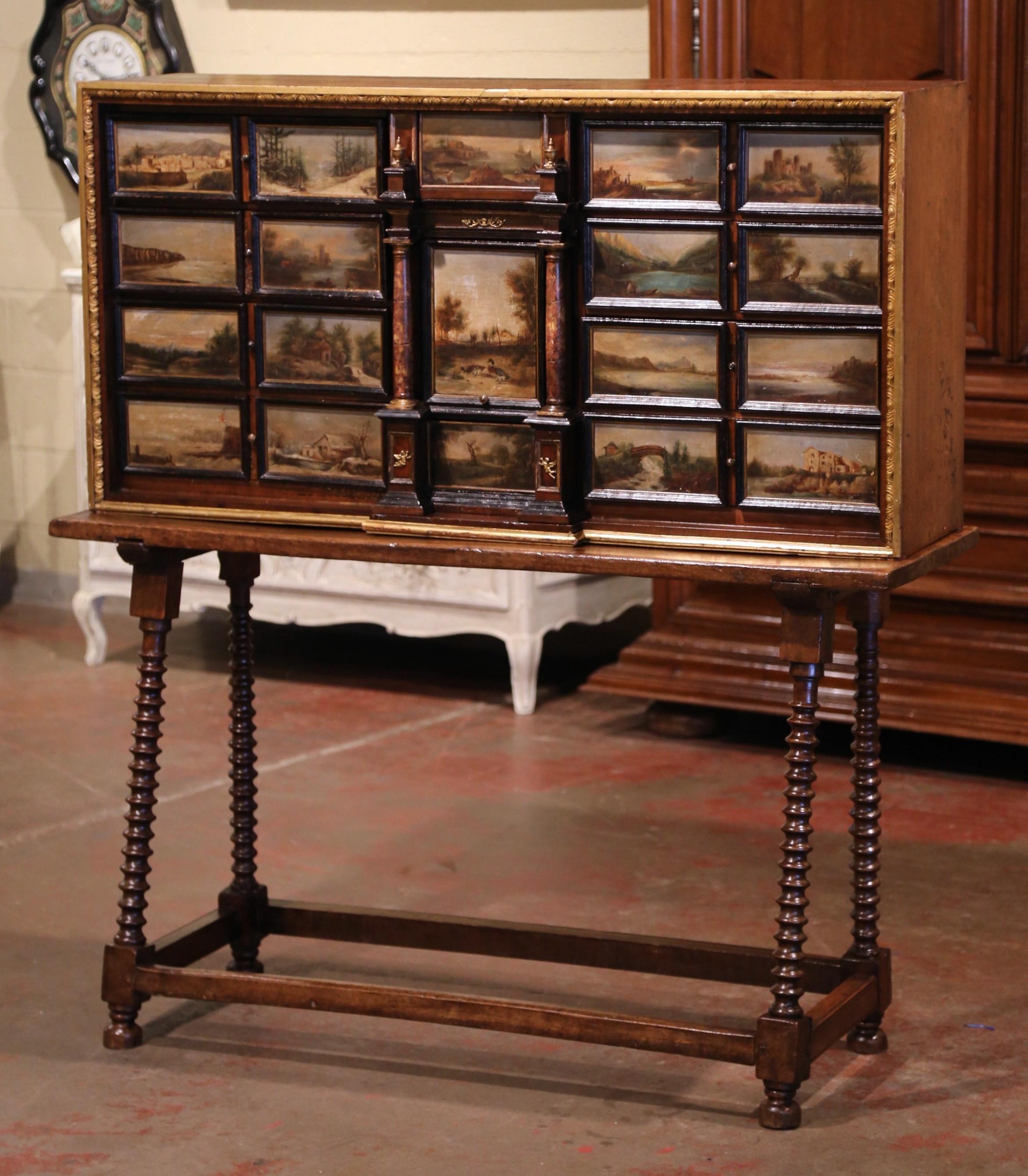 This elegant antique Bargueno (or Vargueño) was crafted in Spain circa 1850; sitting on the original fruitwood table base with turned legs embellished with a bottom stretcher, the cabinet features eleven drawers, including a larger center drawer