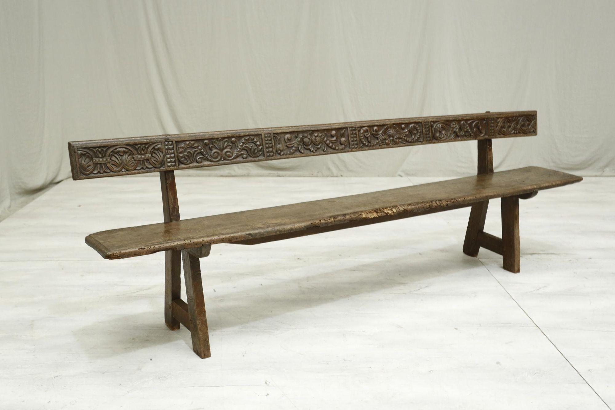 This is a very attractive rustic 19th century Spanish walnut hall bench. The design is very attractively simple but then the deep carved back supports adds a great detail making this a very decorative piece. The whole bench is rustic in its nature