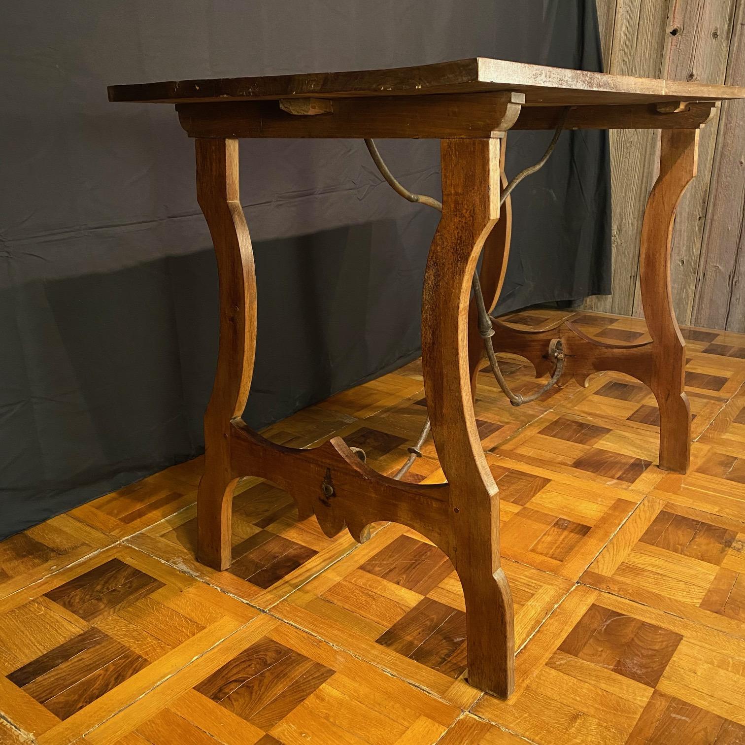 Elegant Spanish walnut Fratina trestle table that could serve as a lovely accent table, console or buffet, or sofa table with beautiful wrought iron stretchers connecting hand carved lyre legs, all in walnut with a rich patina. Found in the South of