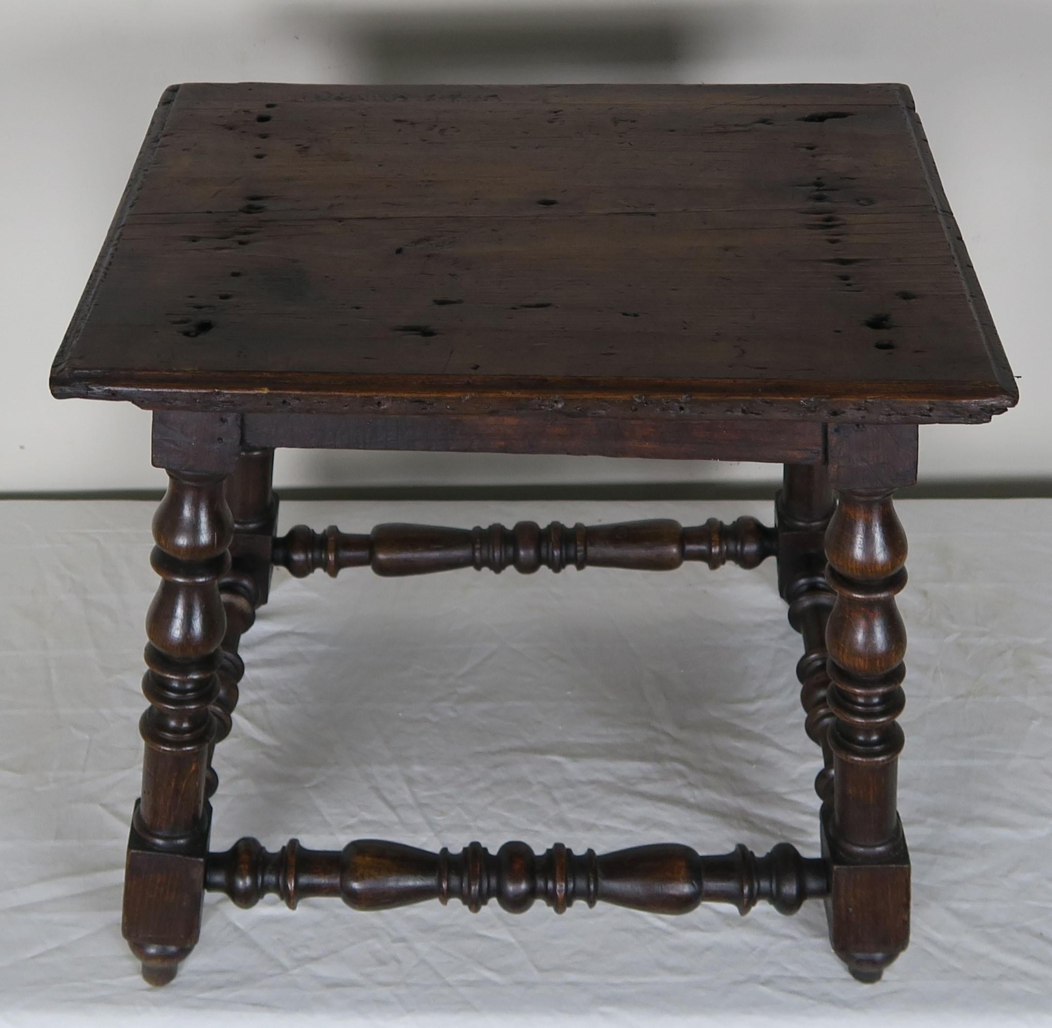 19th century Spanish walnut table standing on four turned legs that are connected by a bottom stretcher.
