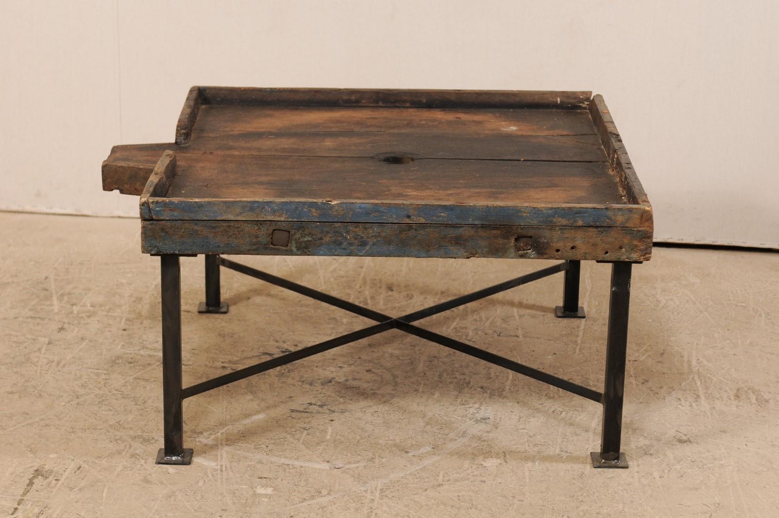 A 19th century Spanish wood trough top coffee table. This fun little coffee table has been custom fashioned from an 19th century Spanish wooden trough, thought to have been used in the processing of olives, and raised upon a custom black metal